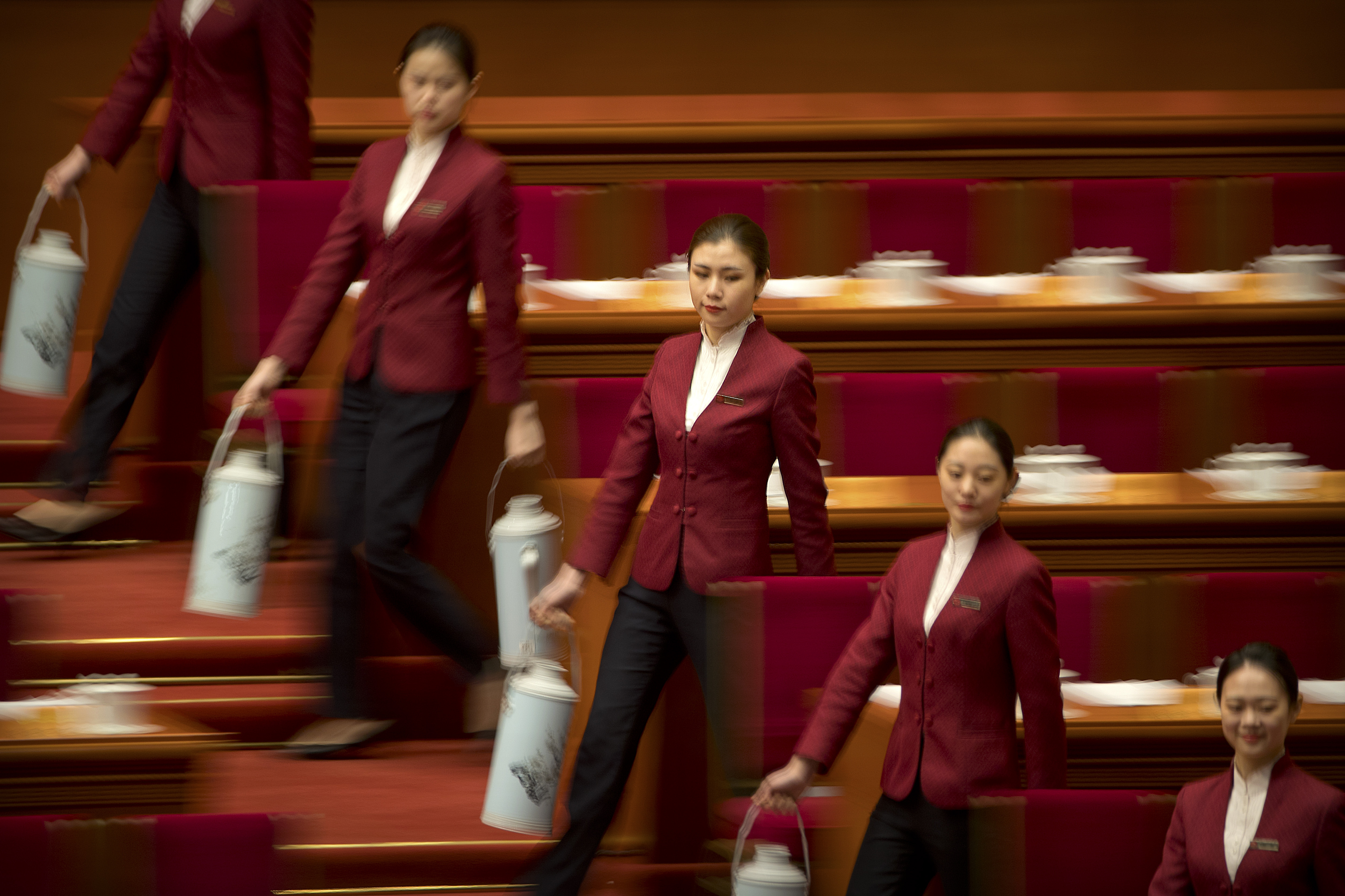 Hostesses carry flasks of water to fill teacups for delegates before the closing session of the Chinese People's Political Consultative Conference (CPPCC) at the Great Hall of the People in Beijing, Wednesday, March 13, 2019. (AP Photo/Mark Schiefelbein)
