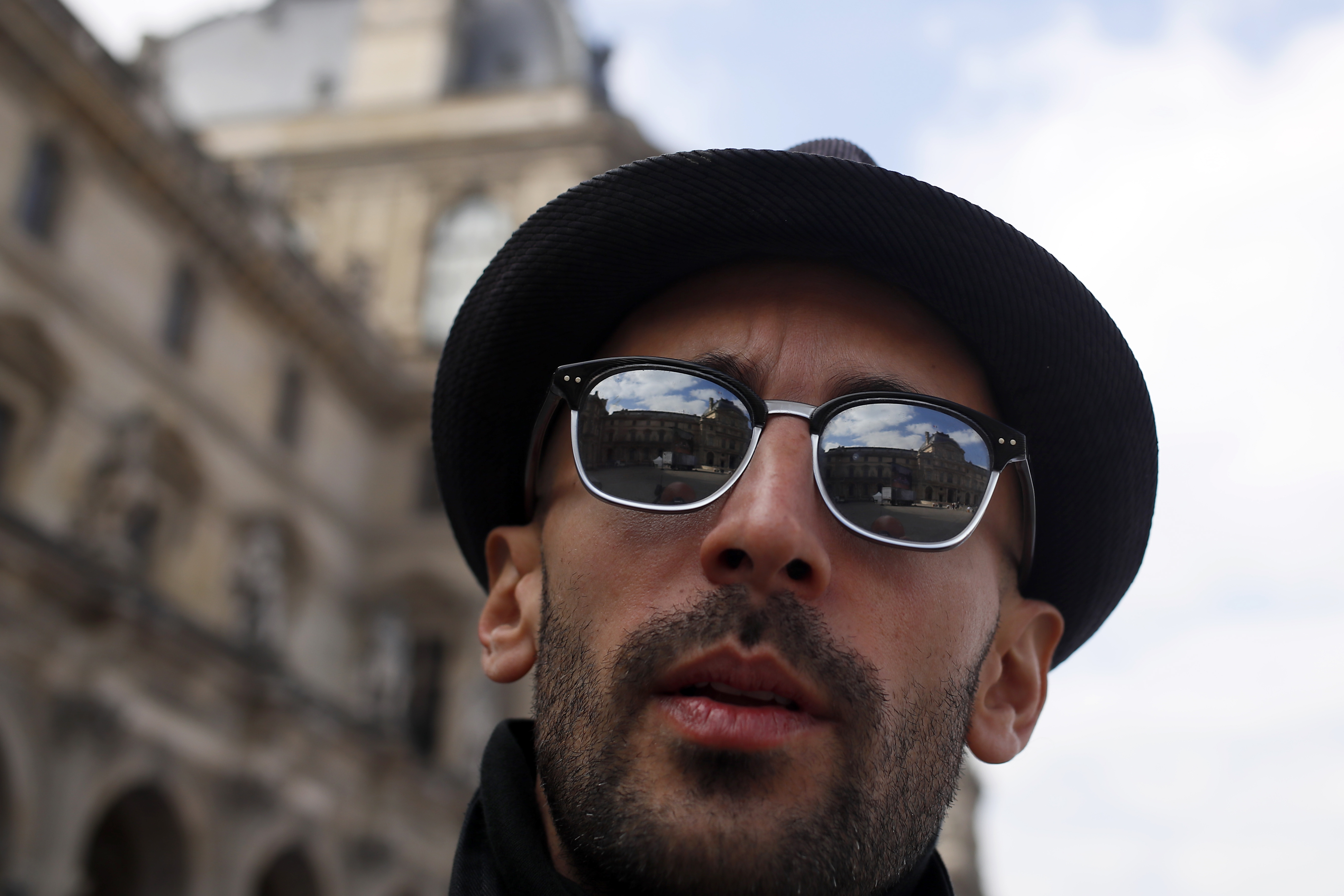 French street artist JR poses in the courtyard of the Louvre Museum near the glass pyramid designed by architect Leoh Ming Pei, in Paris, Wednesday, March 27, 2019 as the Louvre Museum celebrates the 30th anniversary of its glass pyramid. JR project is a giant collage of the pyramid to bring it out of the ground by revealing the foundations of the Napoleon courtyard where it is erected. (AP Photo/Francois Mori)