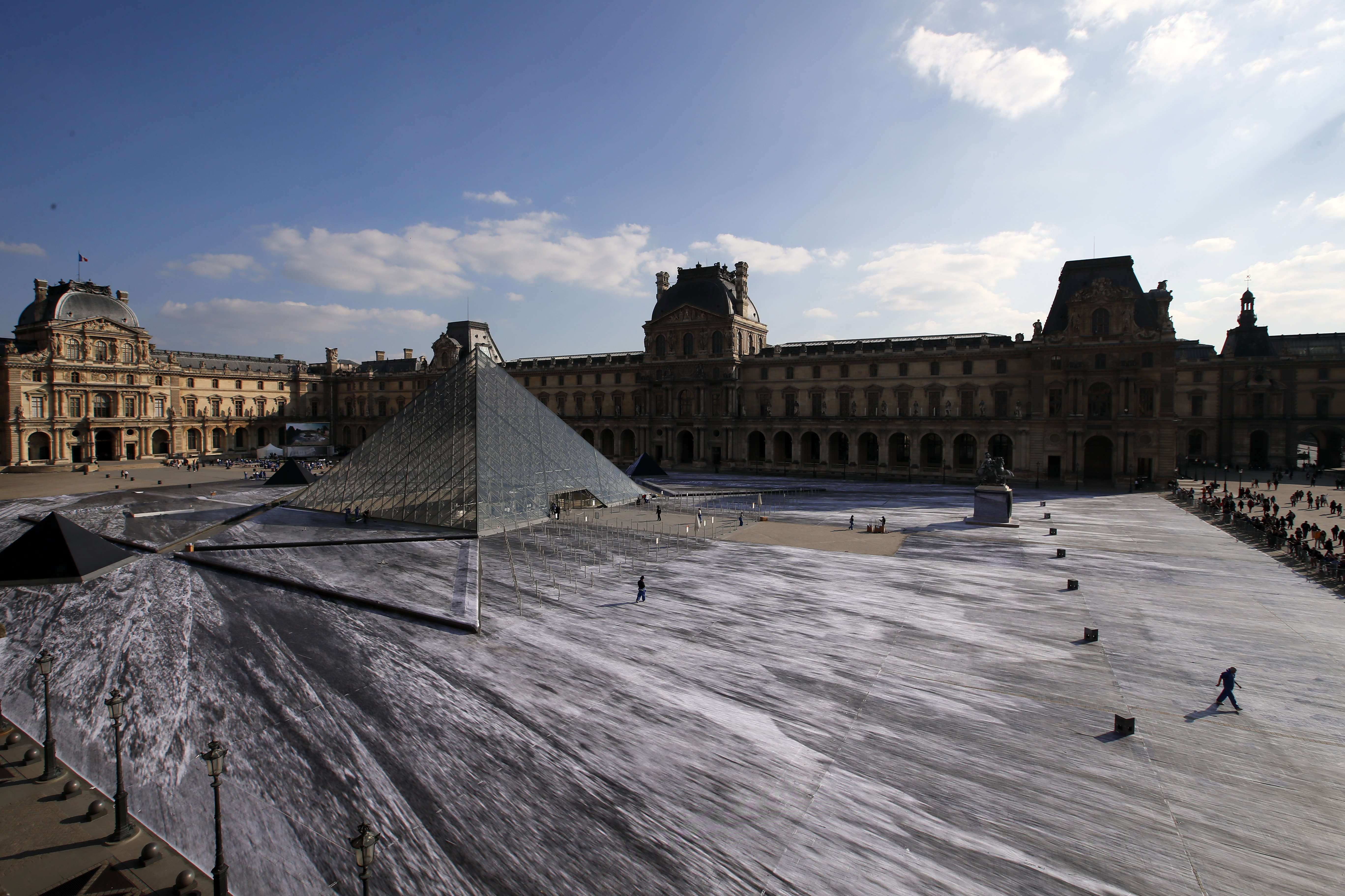 The creation fo French street artist JR is pictured in the courtyard of the Louvre Museum near the glass pyramid designed by Leoh Ming Pei, in Paris, Friday, March 29, 2019 as the Louvre Museum celebrates the 30th anniversary of its glass pyramid. JR project is a giant collage of the pyramid to bring it out of the ground by revealing the foundations of the Napoleon courtyard where it is erected. (AP Photo/Francois Mori)