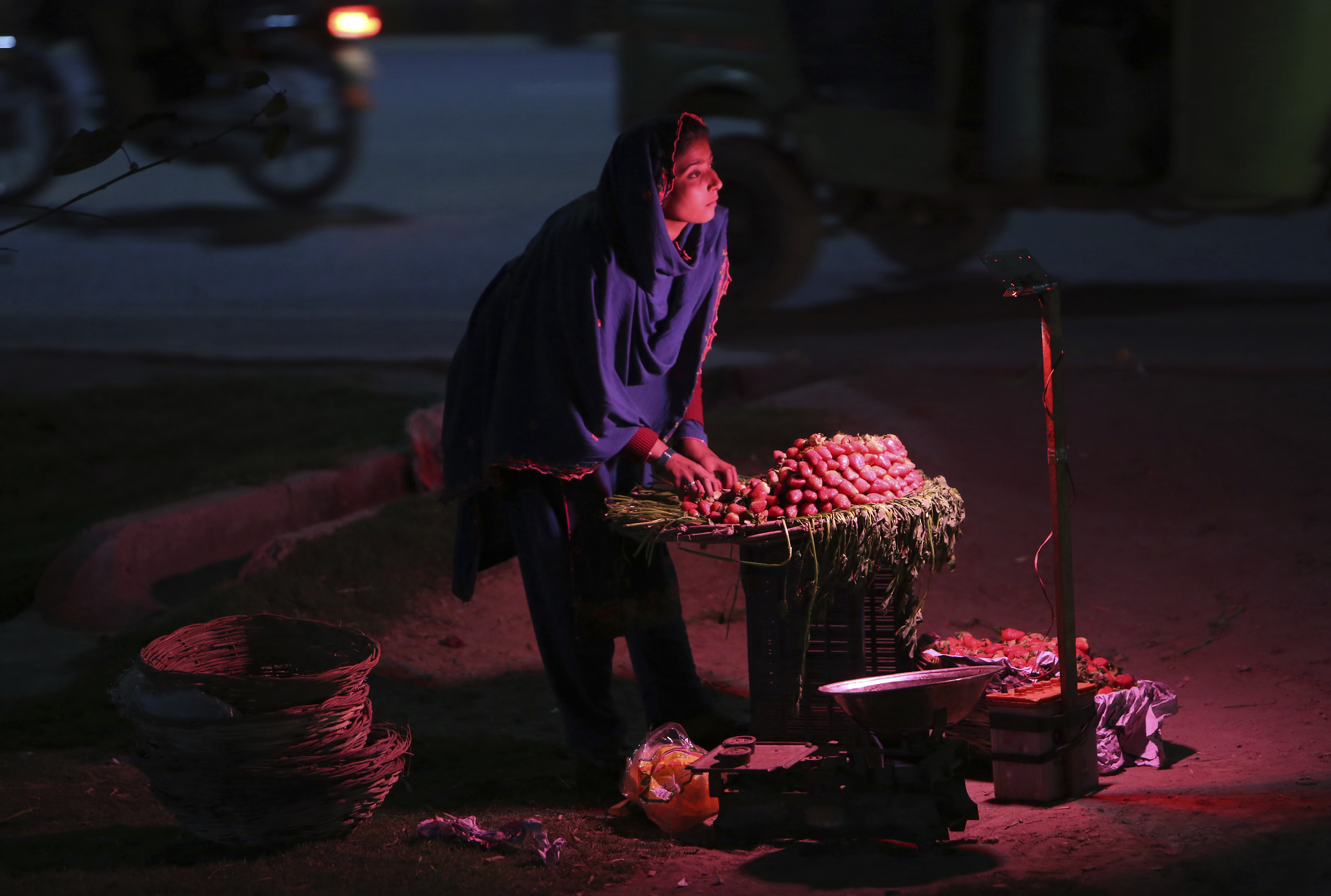 A Pakistani female vendor waits for customers to sell strawberries at a roadside in Lahore, Pakistan, Friday, March 15, 2019. (AP Photo/K.M. Chaudary)