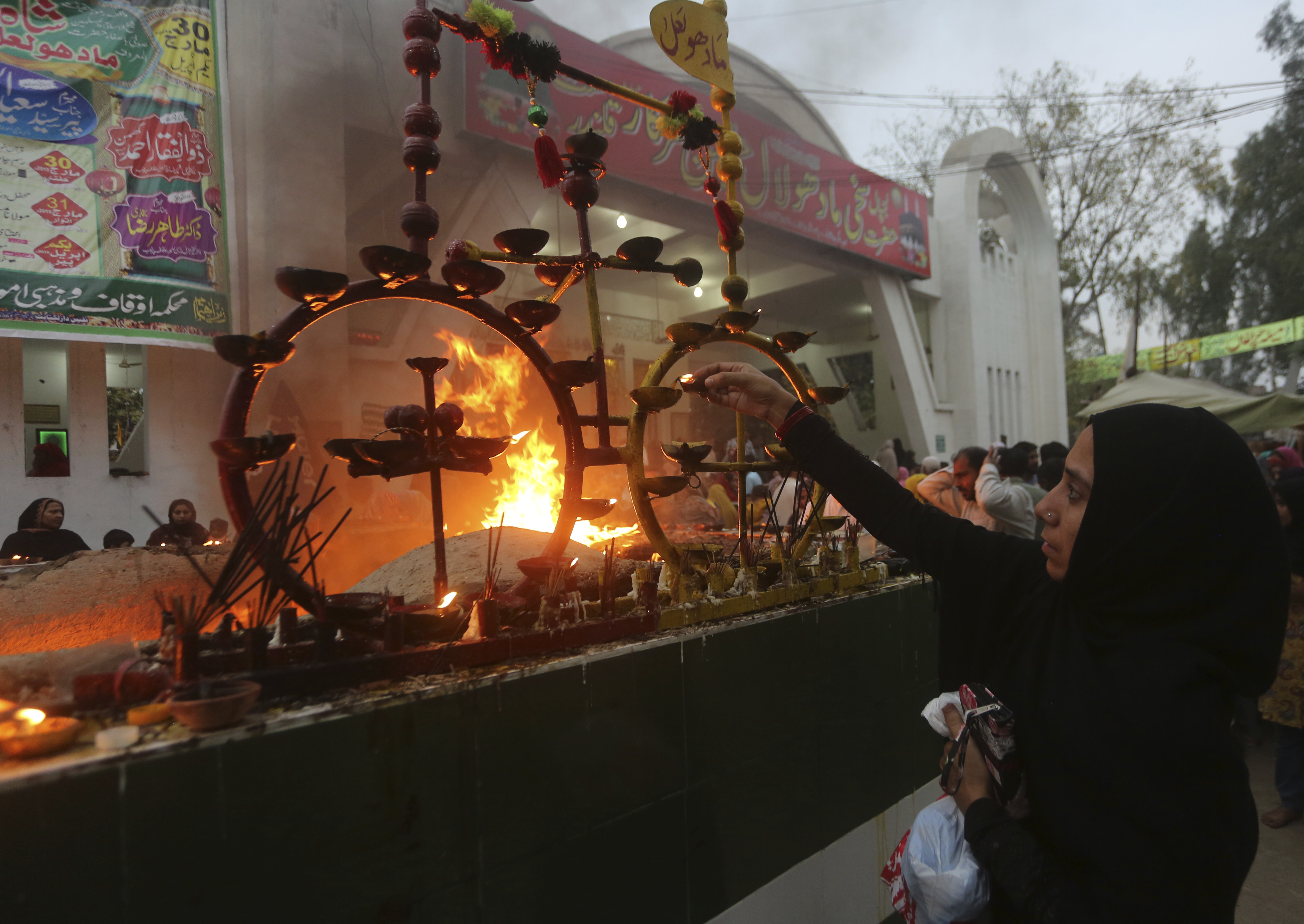 A Pakistani pilgrim lights earthen lamps at a shrine in Lahore, Pakistan, Thursday, March 28, 2019.  People traditionally visit shrines on Thursdays and Fridays to light oil lamps, incense sticks and pray to get their wishes fulfilled. (K.M. Chaudhry)