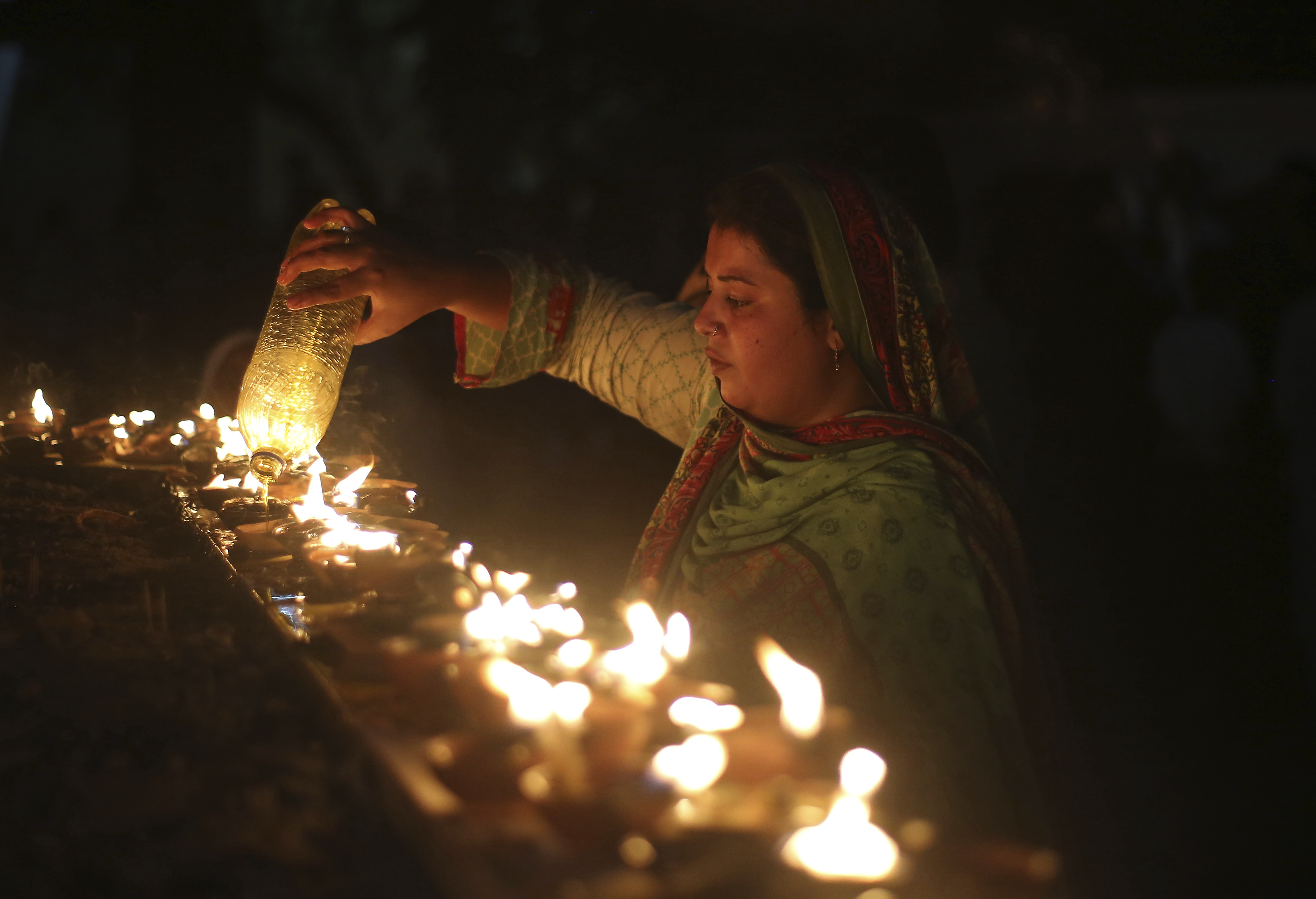 A Pakistani pilgrim pours oil in earthen lamps at a shrine in Lahore, Pakistan, Thursday, March 28, 2019.  People traditionally visit shrines on Thursdays and Fridays to light oil lamps, incense sticks and pray to get their wishes fulfilled. (K.M. Chaudhry)