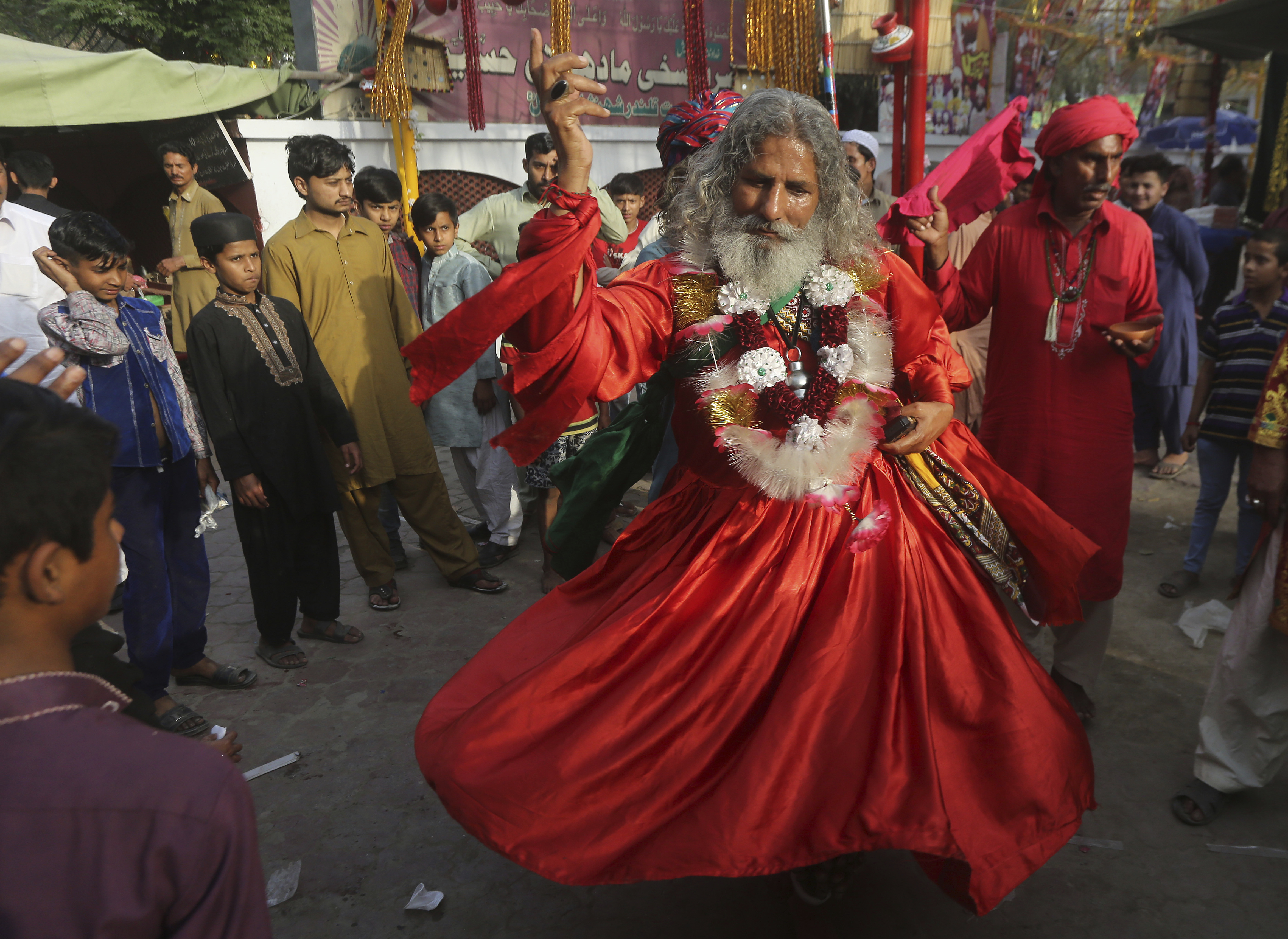 People look at a devotee dances at the shrine of Madhu Lal Shah Hussain, a poet also regarded as a Sufi saint, during an annual festival to celebrate him in Lahore, Pakistan, Friday, March 29, 2019. The annual festival to commemorate Shah Hussain (1538-1599) started with thousands of people expected to visit the shrine. (AP Photo/K.M Chaudary)