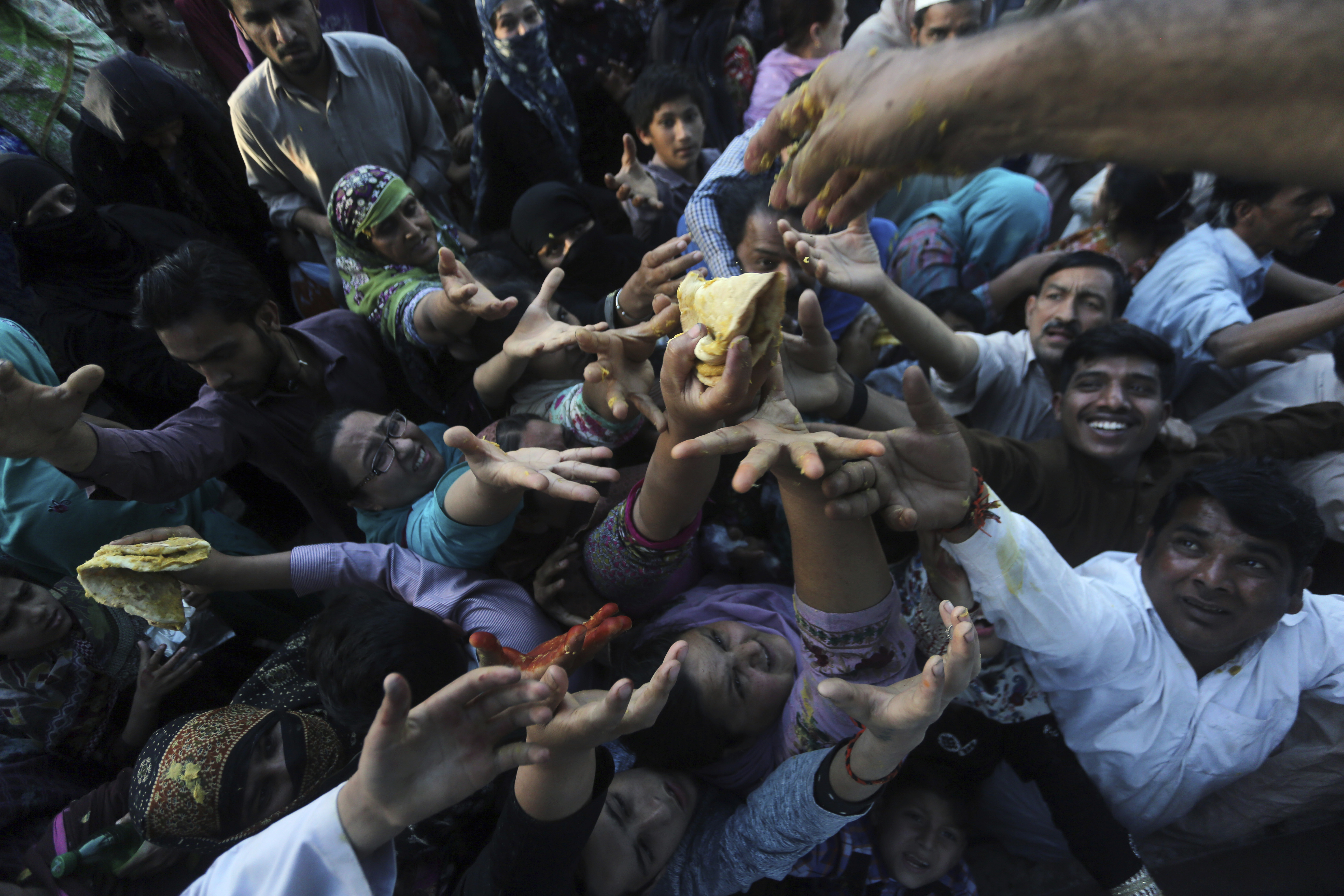 Pakistani pilgrims jostle for free food distributed at the shrine of Madhu Lal Shah Hussain, a poet also regarded as a Sufi saint, during an annual festival to celebrate him in Lahore, Pakistan, Monday, April 1, 2019. The annual festival to commemorate Shah Hussain (1538-1599) started with thousands of people expected to visit the shrine. (AP Photo/K.M Chaudary)