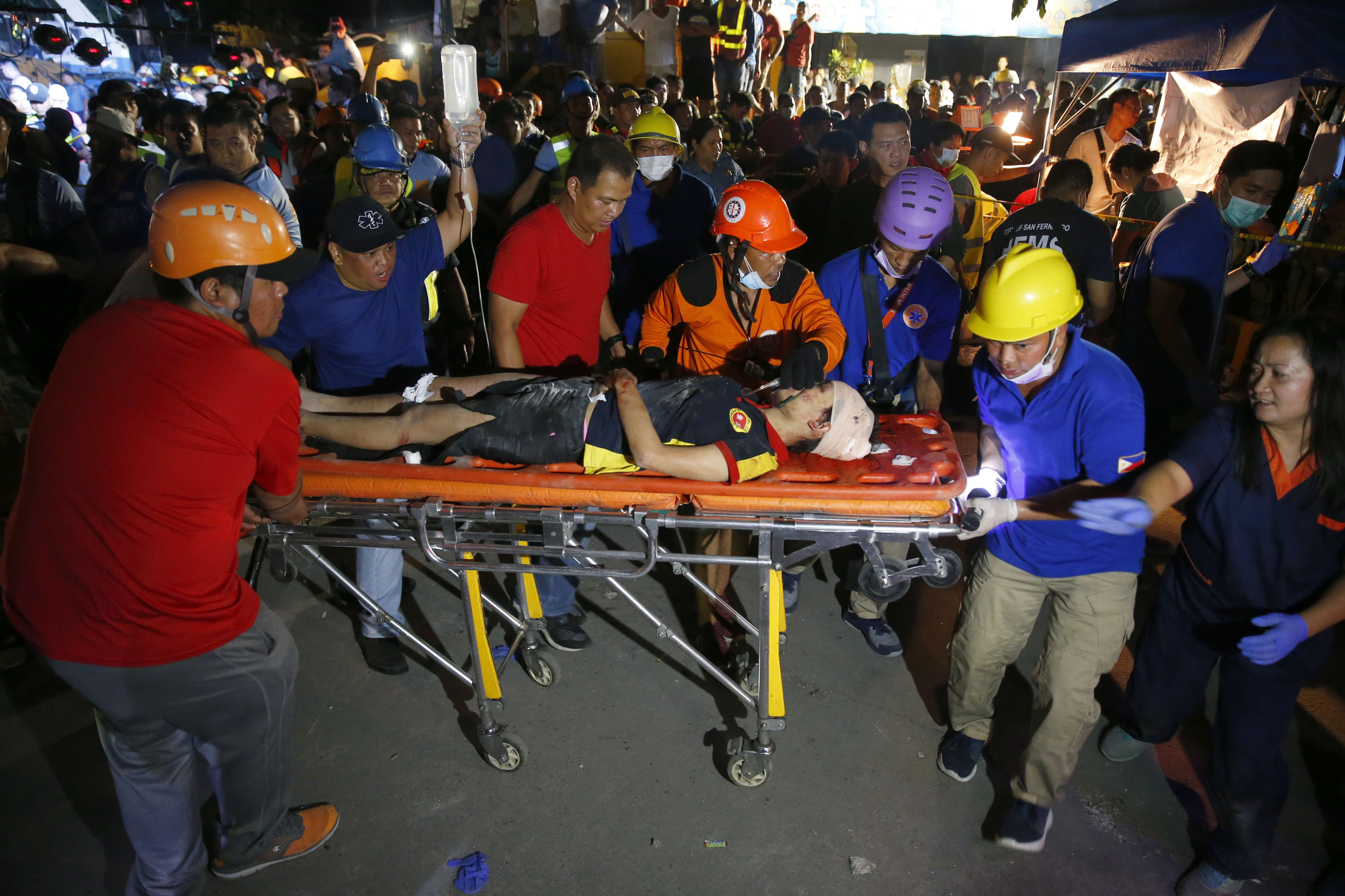 Rescuers carry a victim to a waiting ambulance after following a magnitude 6.1 earthquake that caused the collapse of a commercial building in Porac township, Pampangan province north of Manila, Philippines Monday, April 22, 2019. A strong earthquake struck the northern Philippines Monday trapping some people in a collapsed building, damaged an airport terminal and knocked out power in at least one province, officials said. (AP Photo/Bullit Marquez)