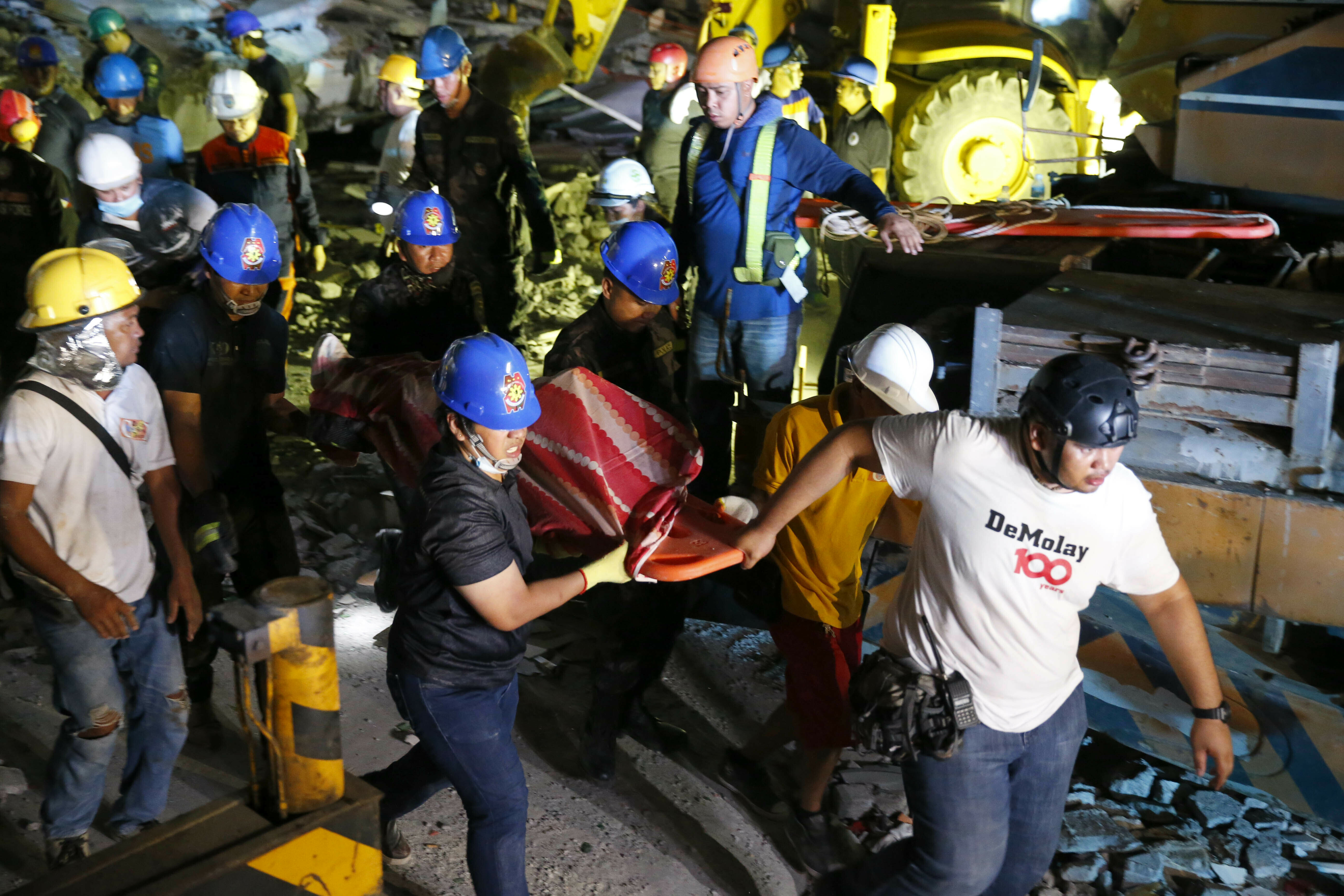 Rescuers carry a victim to a waiting ambulance after being pulled out from the rubble of a collapsed building following Monday's magnitude 6.1 earthquake in Porac township, Pampangan province north of Manila, Philippines Tuesday, April 23, 2019. A strong earthquake struck the northern Philippines Monday trapping some people in a collapsed building, damaging an airport terminal and knocking out power in at least one province, officials said. (AP Photo/Bullit Marquez)