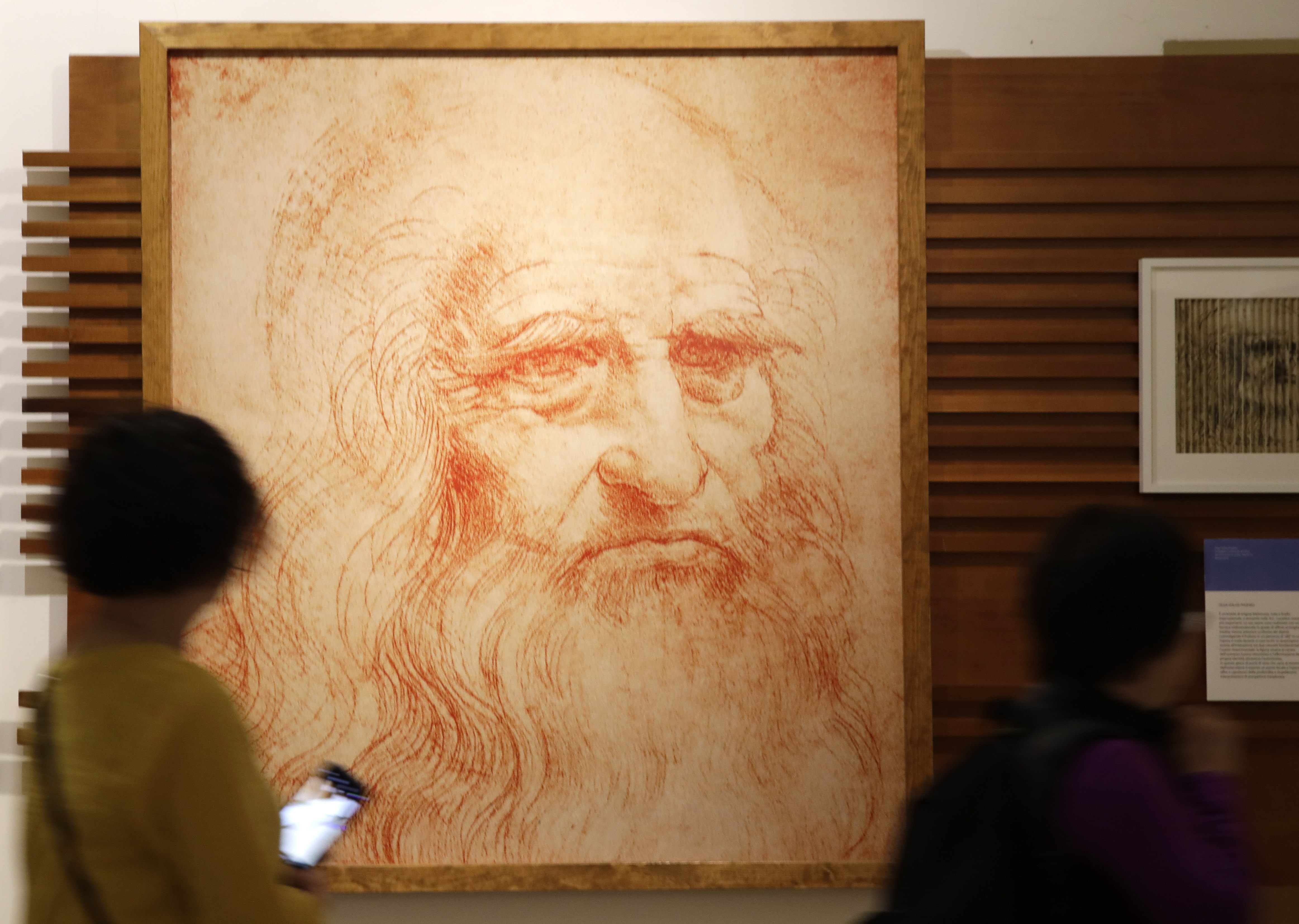 Visitors look at a portrait drawing of Italian Renaissance painter, scientist and inventor Leonardo Da Vinci during a permanent exhibition on Da Vinci, on the exact day commemorating the 500th anniversary of his death, in Rome, Thursday, May 2, 2019. Leonardo died in Amboise, France, on May 2, 1519.  (AP Photo/Alessandra Tarantino)