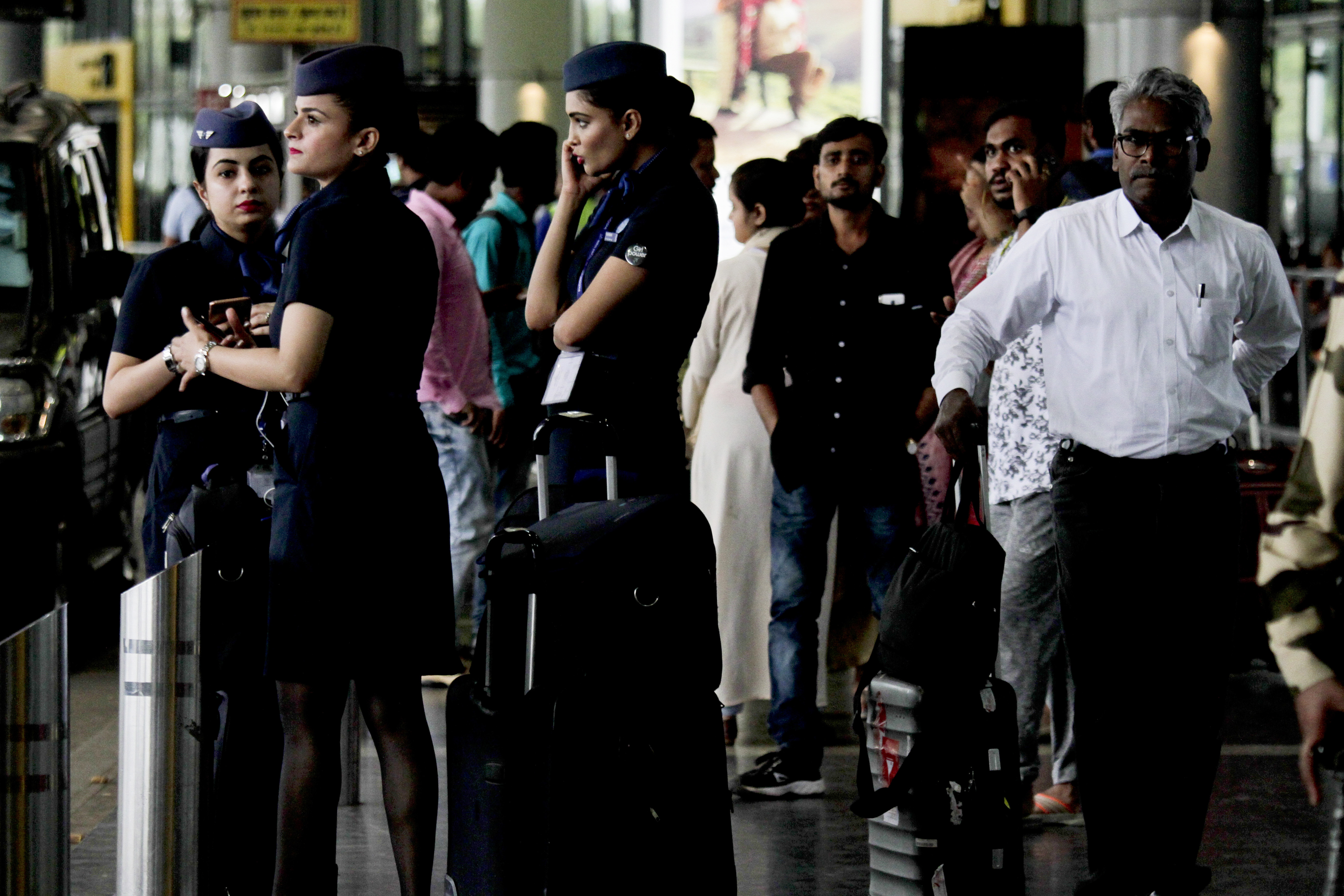Stewardess and stranded passengers wait outside the Netaji Subhas Chandra Bose international airport after all flights were suspended following cyclone Fani landfall in eastern coast, in Kolkata, India, Friday, May 3, 2019. Cyclone Fani has made landfall on India's eastern coast as a grade 5 storm, lashing the emptied beaches with rain and wind gusting up to 205 kilometers (127 miles) per hour. (AP Photo/Bikas Das)