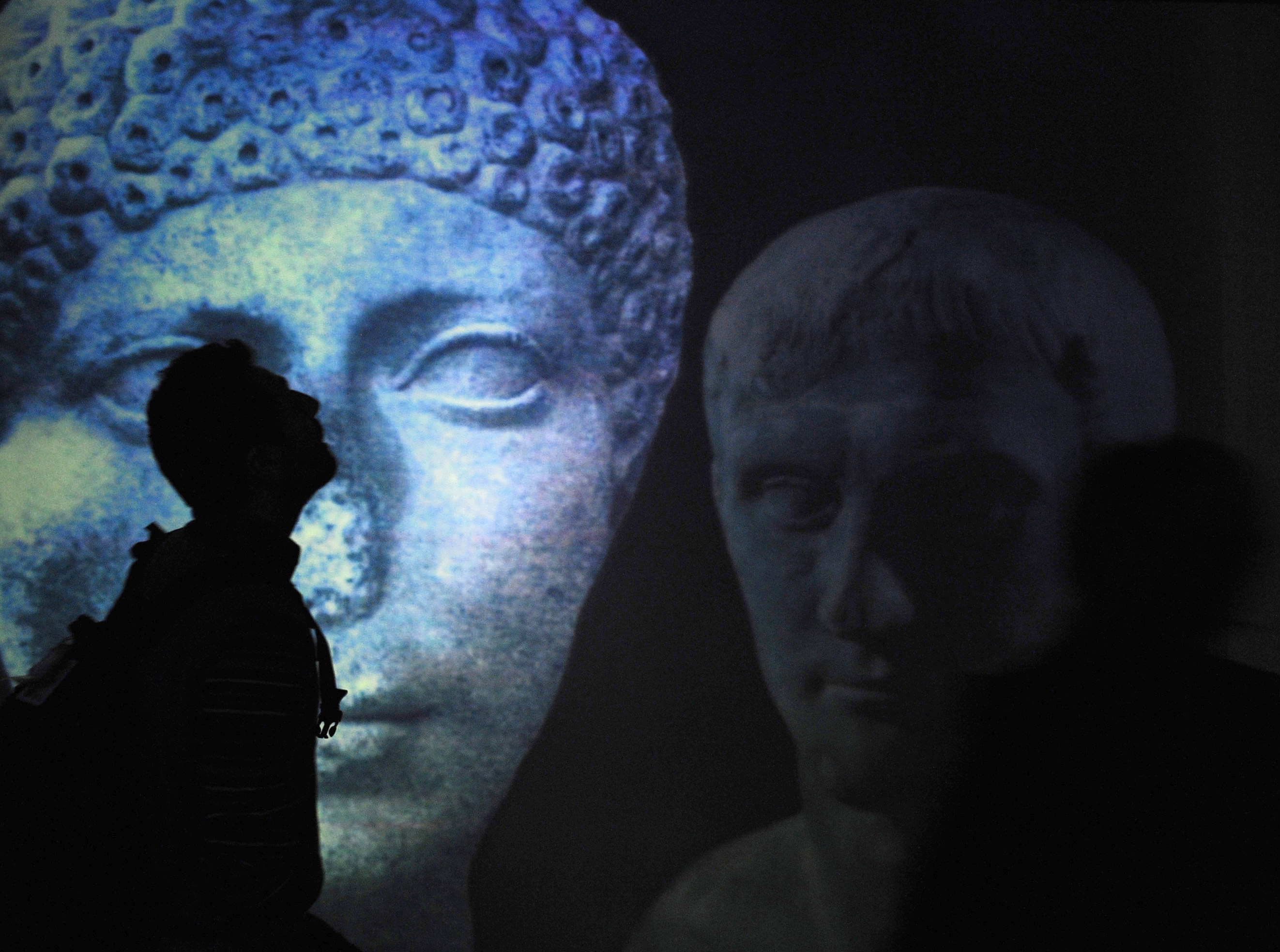 A visitor is silhouetted in front of giant reproductions of statues at the MAV Virtual Archeological Museum in Ercolano, near Naples, southern Italy, on Thursday, Nov. 27, 2008. The museum, installed with infrared cameras to pick up on body movements, opened in July 2008. It hosts multimedia exhibitions on the ancient towns of Pompeii and Ercolano (Herculaneum), in which visitors can interact with screens to remove ashes and unveil a mosaic or remove steam and unveil a woman being bathed, as the daily life of the time has been recreated in 3D installations. (AP Photo/Salvatore Laporta)
