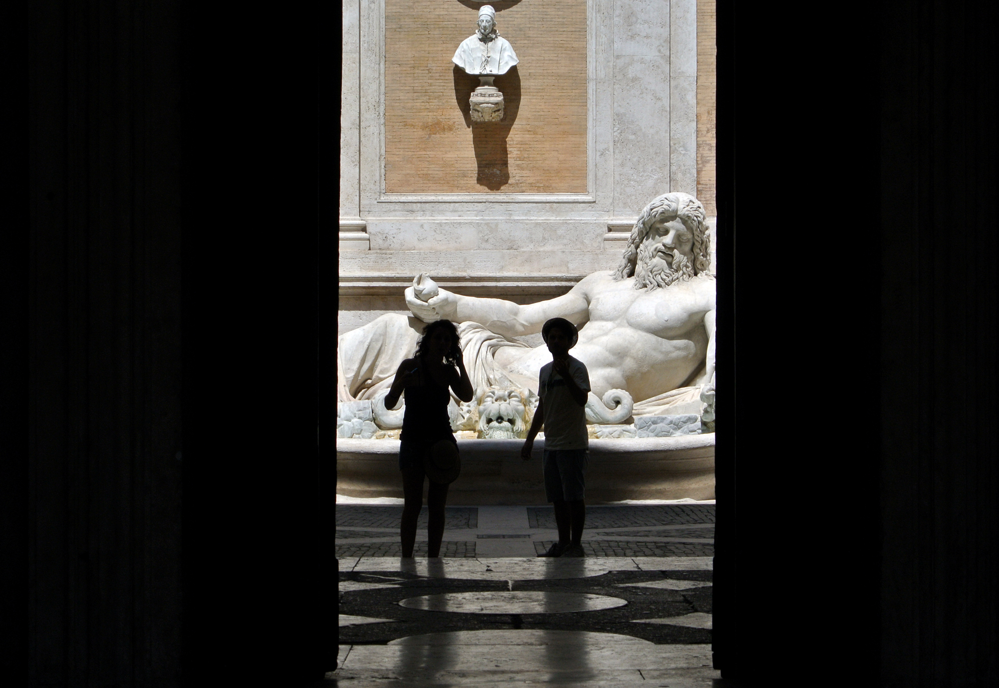 Tourists admire the  statue of  Marforio river at the Capitoline museums in Rome, Saturday, July 27, 2013. On Saturday many Italian museums will stay open in the evening. (AP Photo/Gregorio Borgia)