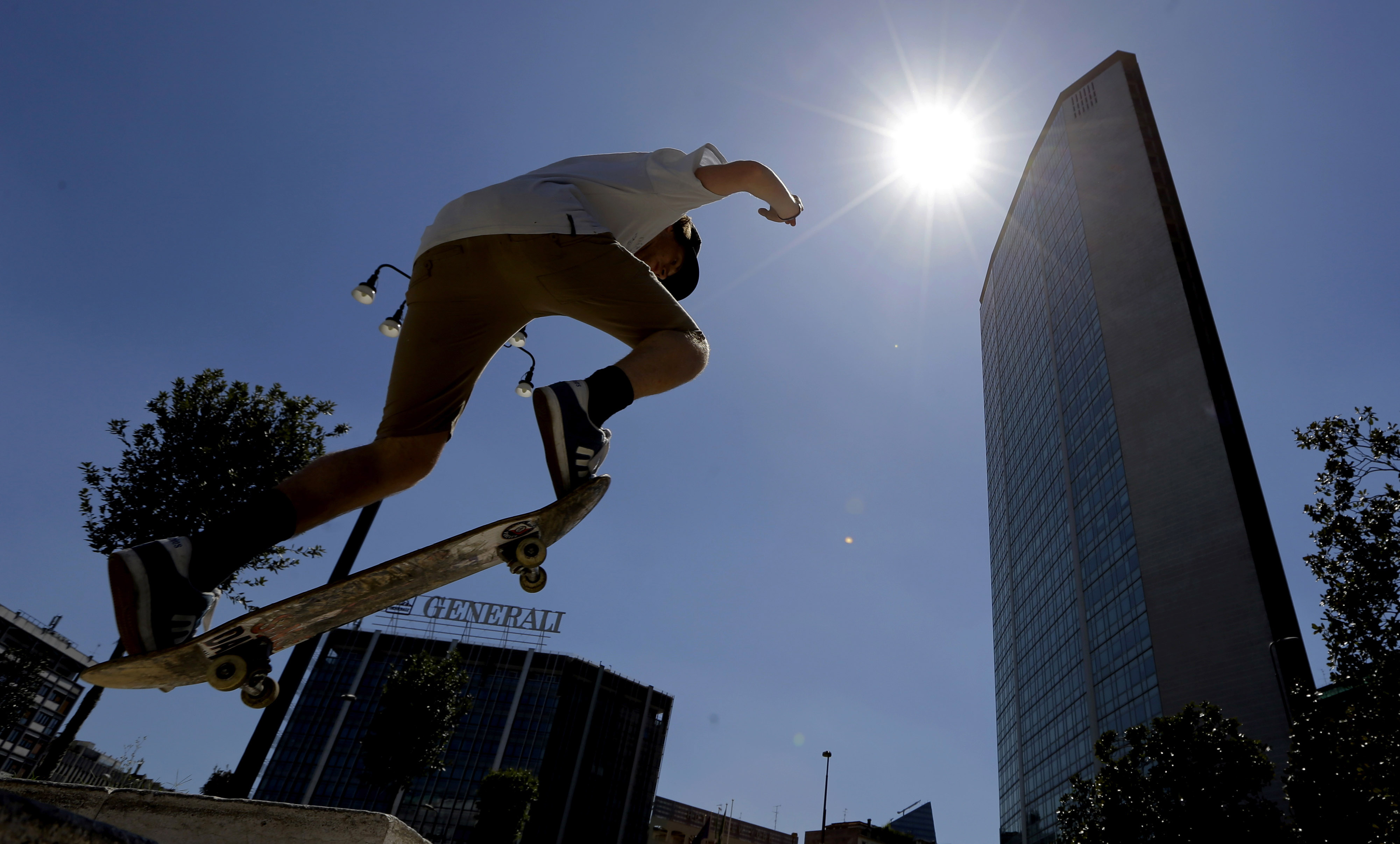 A skater performs in front of the Pirelli skyscraper in downtown Milan, Italy, Wednesday, July 31, 2013. Youths practice skate boarding in desert streets as temperatures reached peaks as high as 35 degrees Celsius (95 FArenheit).  (AP Photo/Luca Bruno)