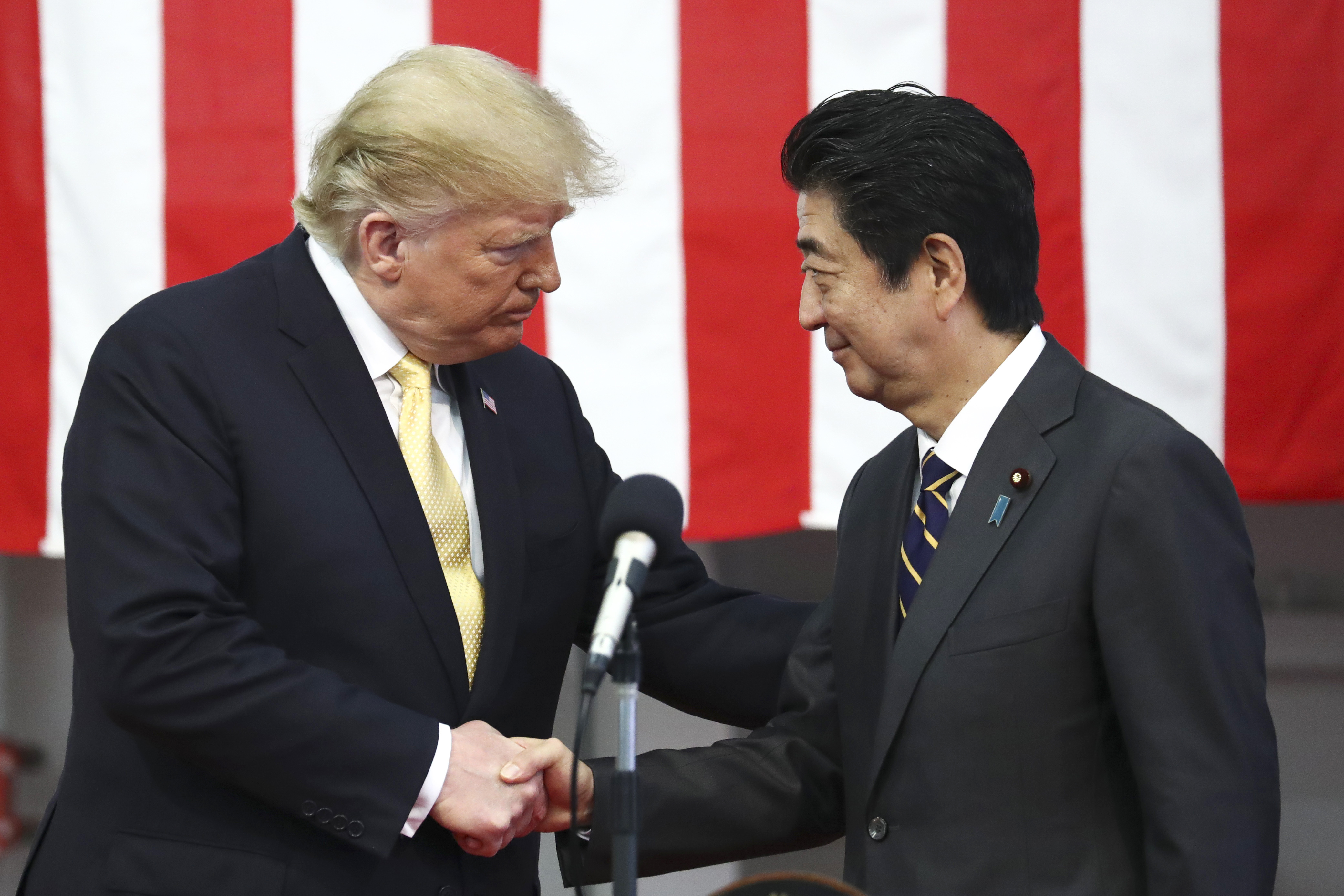 U.S. President Donald Trump, left, shakes hands with Japan's Prime Minister Shinzo Abe during delivering a speech to Japanese and U.S. troops as they aboard Japan Maritime Self-Defense Force's (JMSDF) helicopter carrier DDH-184 Kaga at JMSDF Yokosuka base in Yokosuka, south of Tokyo, Tuesday, May 28, 2019. (Athit Perawongmetha/Pool Photo vi AP)
