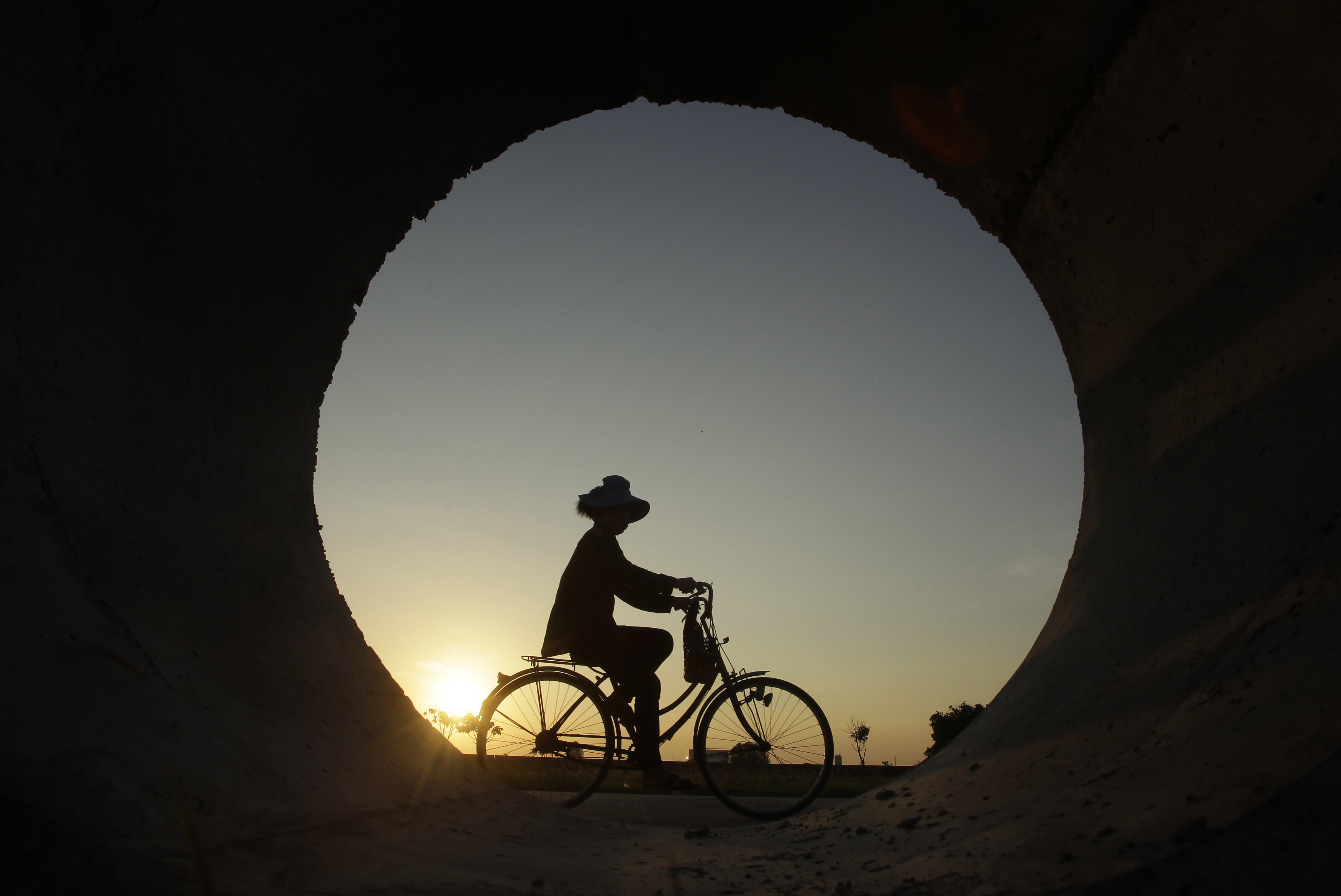 A construction worker cycles to head for working in Samroang village outside Phnom Penh, Cambodia, Tuesday, May 21, 2019. (AP Photo/Heng Sinith)