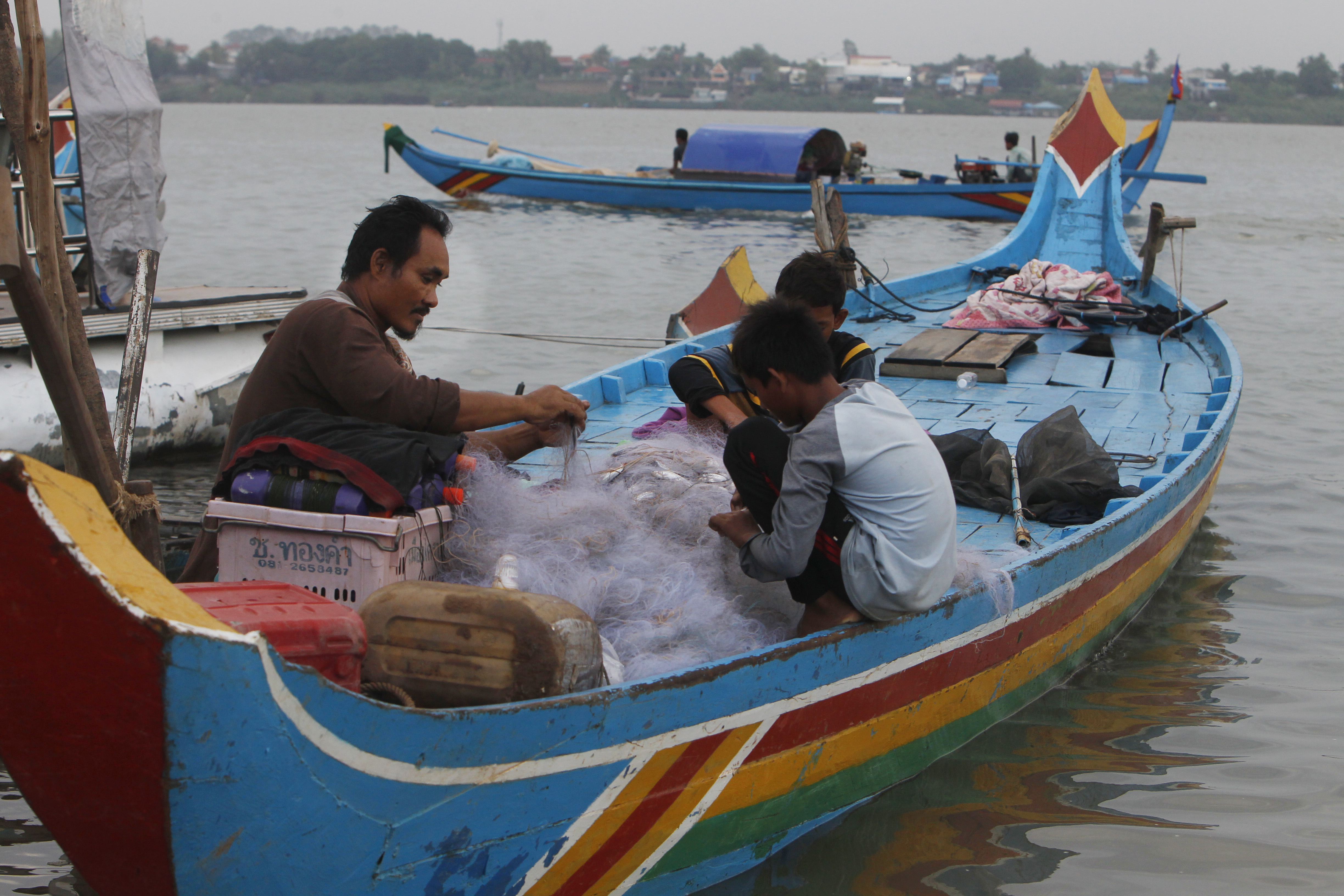 Cambodian Muslims collect fish from the fishing net on their family's wooden boat on Mekong River bank near Phnom Penh, Cambodia, Wednesday, May 29, 2019. (AP Photo/Heng Sinith)