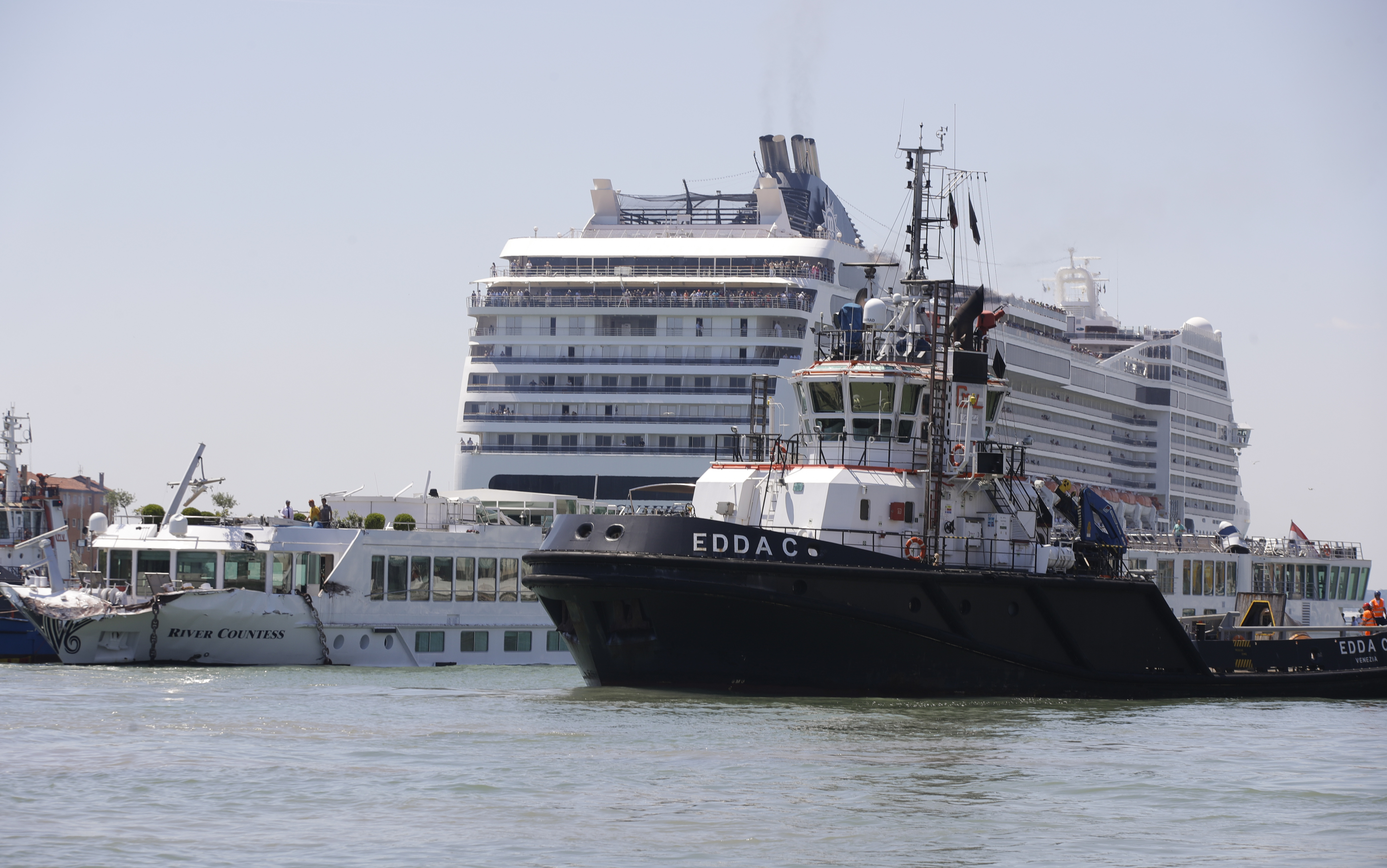 A tourist river boat, left, is dwarfed by the MSC Magnifica cruise ship passing by, in Venice, Italy, Sunday, June 2, 2019. The towering cruise ship MSC Opera has struck a dock and a tourist river boat on a busy canal in Venice. Italian media report that at least five people have been injured in the crash. (AP Photo/Luca Bruno)