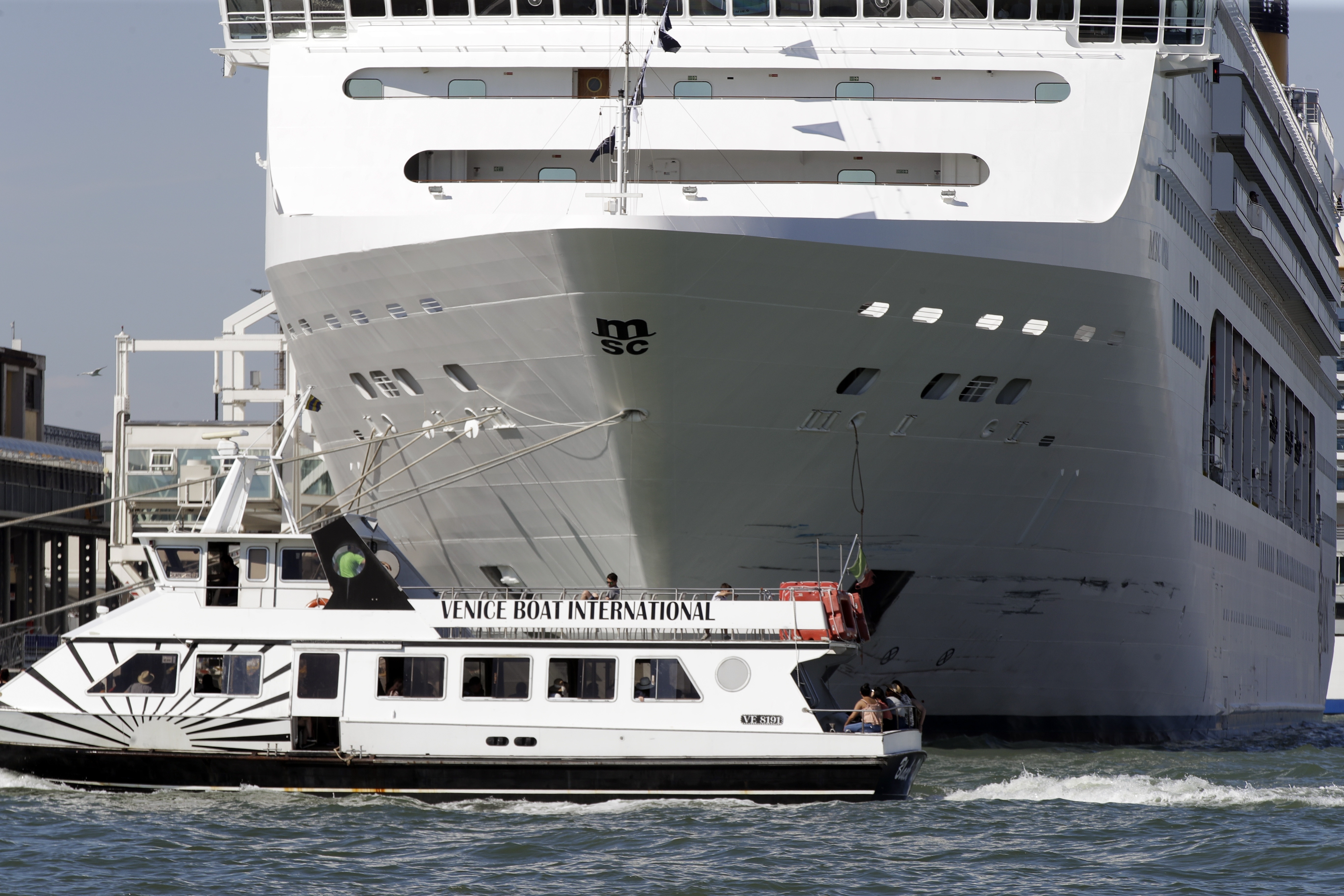 A boat passes by the MSC Opera cruise ship moored at the Venice harbor, Italy, Sunday, June 2, 2019. A towering, out-of-control cruise ship rammed into a dock and a tourist river boat on a busy Venice canal. Italian media reported that at least five people were injured. (AP Photo/Luca Bruno)