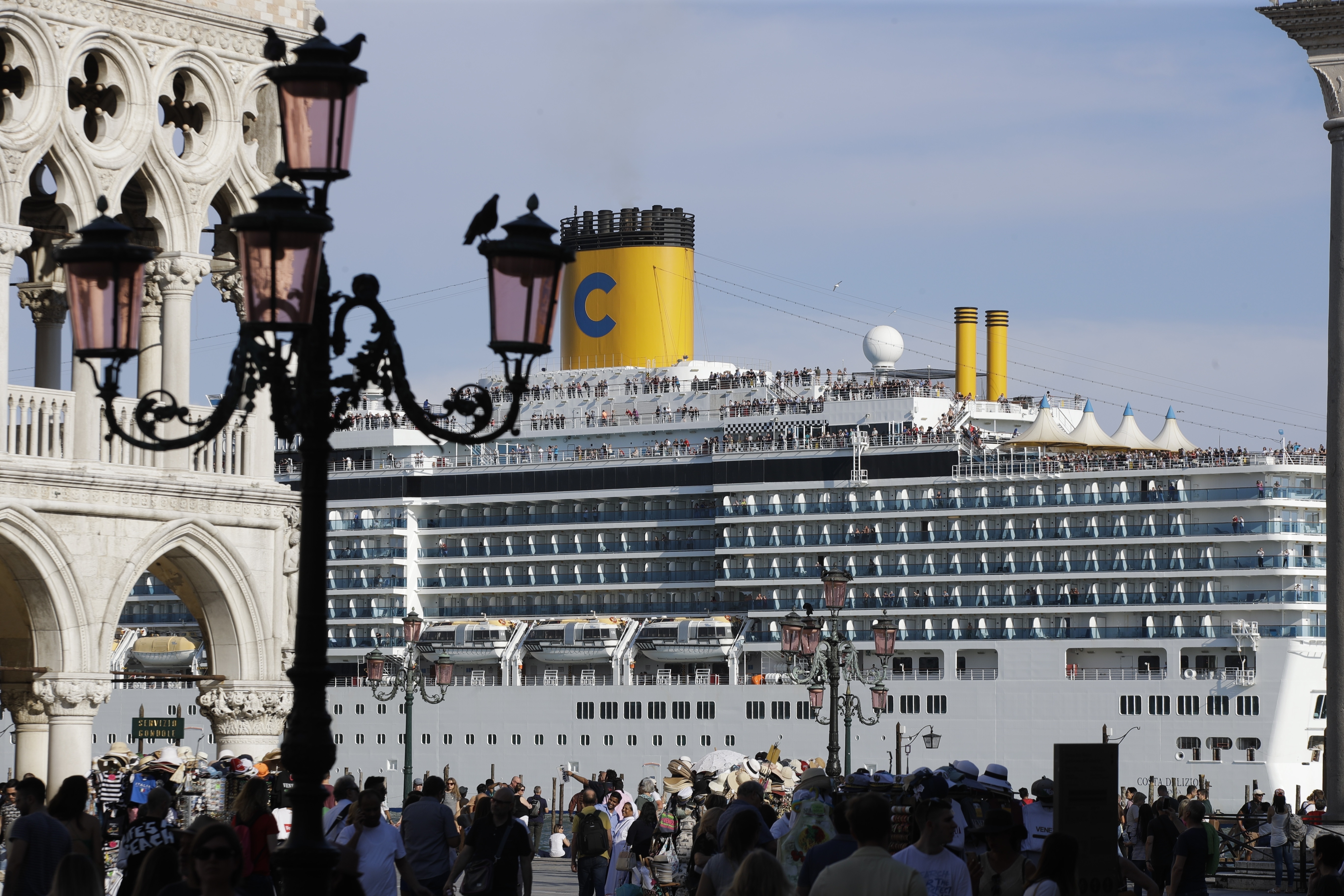 A cruise ship passes by St. Mark's Square filled with tourists, in Venice, Italy, Sunday, June 2, 2019. Groups that want to ban cruise ships on Venice's busy canals say a collision that injured four tourists has served as a wake-up call. Opponents say cruise ships are out-of-scale for Venice, cause pollution, threaten the lagoon's ecosystem and dangerous. (AP Photo/Luca Bruno)