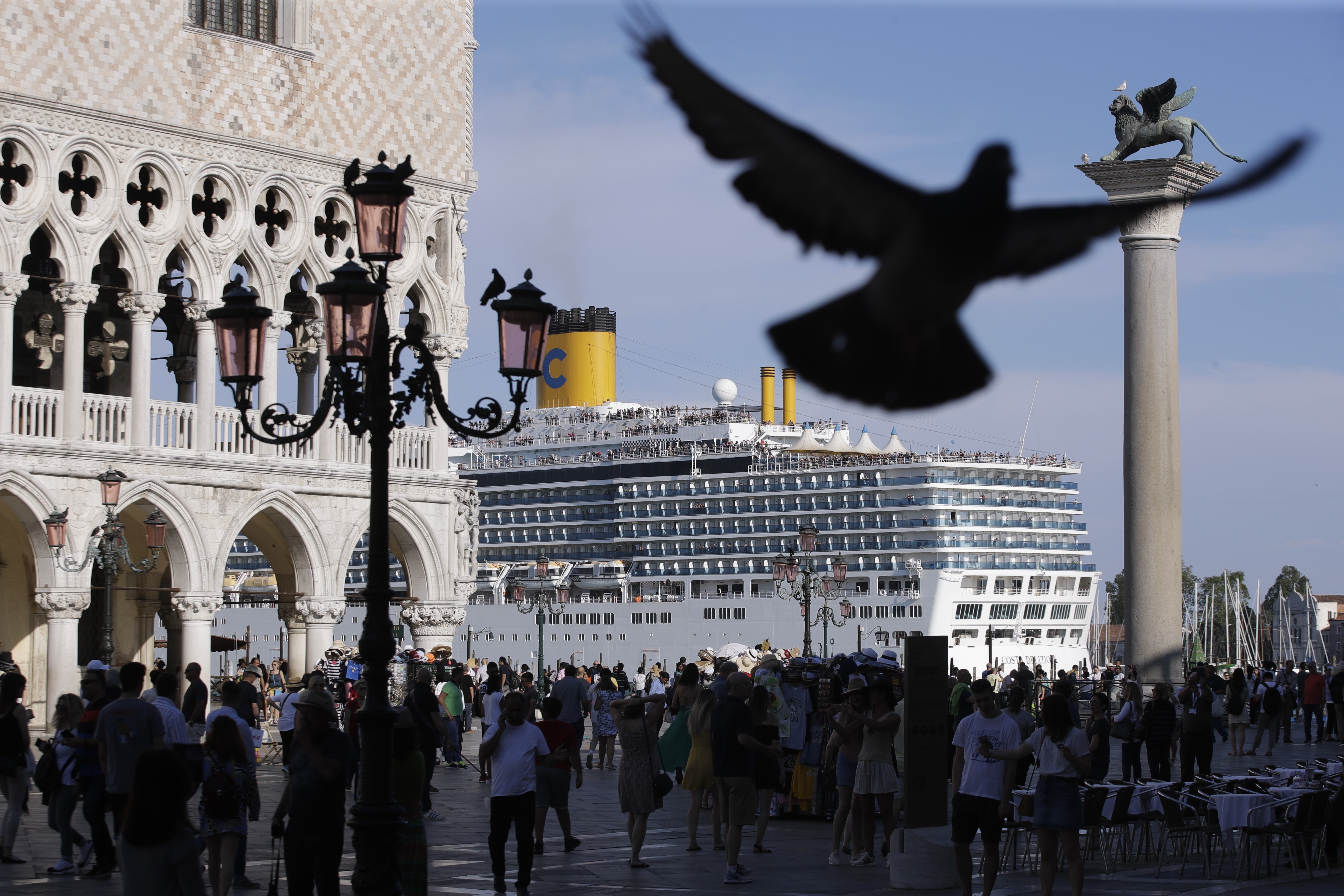 A cruise ship passes by St. Mark's Square filled with tourists, in Venice, Italy, Sunday, June 2, 2019. Groups that want to ban cruise ships on Venice's busy canals say a collision that injured four tourists has served as a wake-up call. Opponents say cruise ships are out-of-scale for Venice, cause pollution, threaten the lagoon's ecosystem and dangerous. (AP Photo/Luca Bruno)
