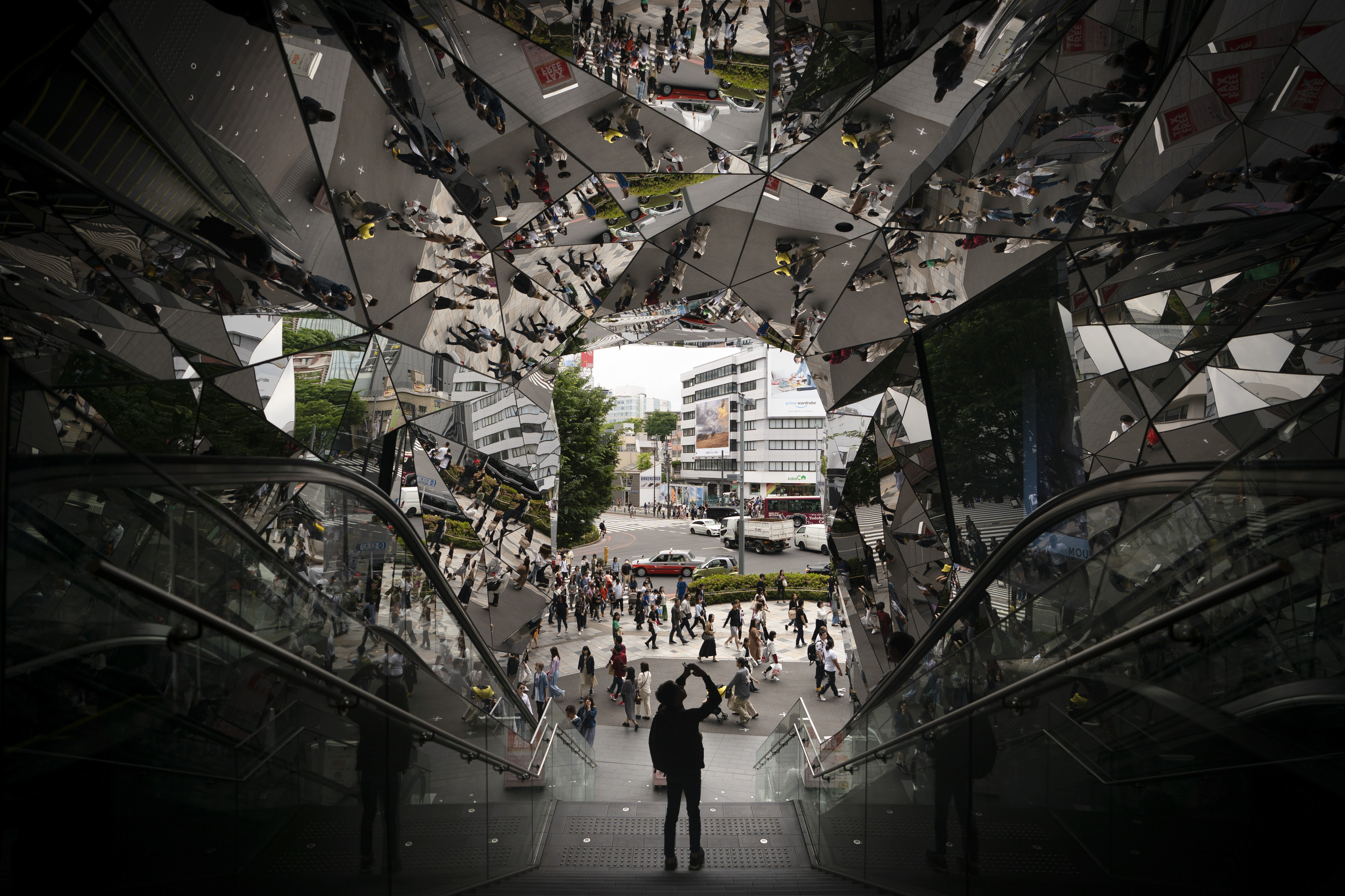 A tourist takes pictures in the entrance way to a shopping mall decorated with mirrors Saturday, May 18, 2019, in Harajuku district of Tokyo. (AP Photo/Jae C. Hong)