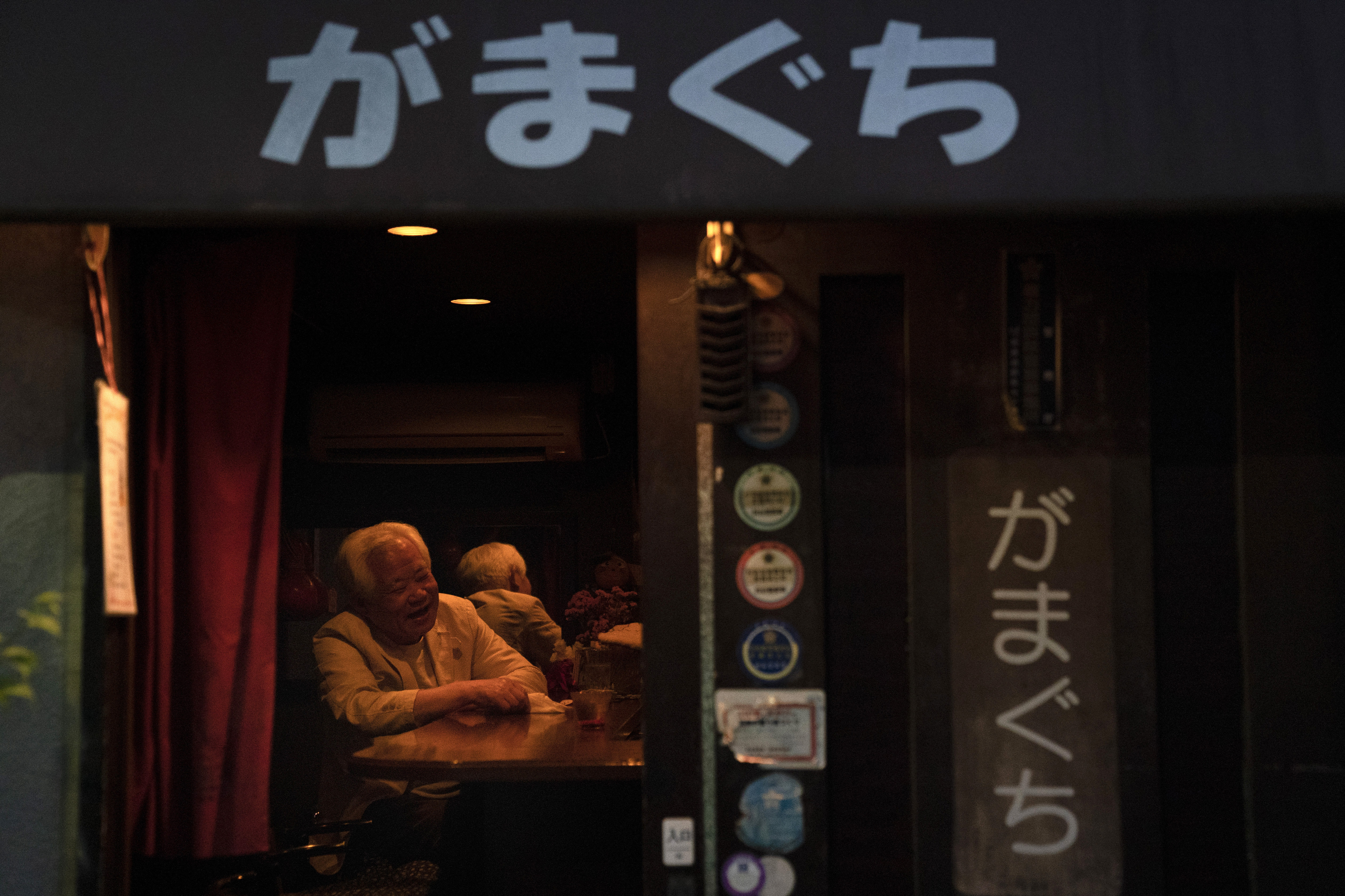 A man shares a laugh with a bartender at a tiny bar Saturday, May 18, 2019, in Shinjuku district in Tokyo. (AP Photo/Jae C. Hong)