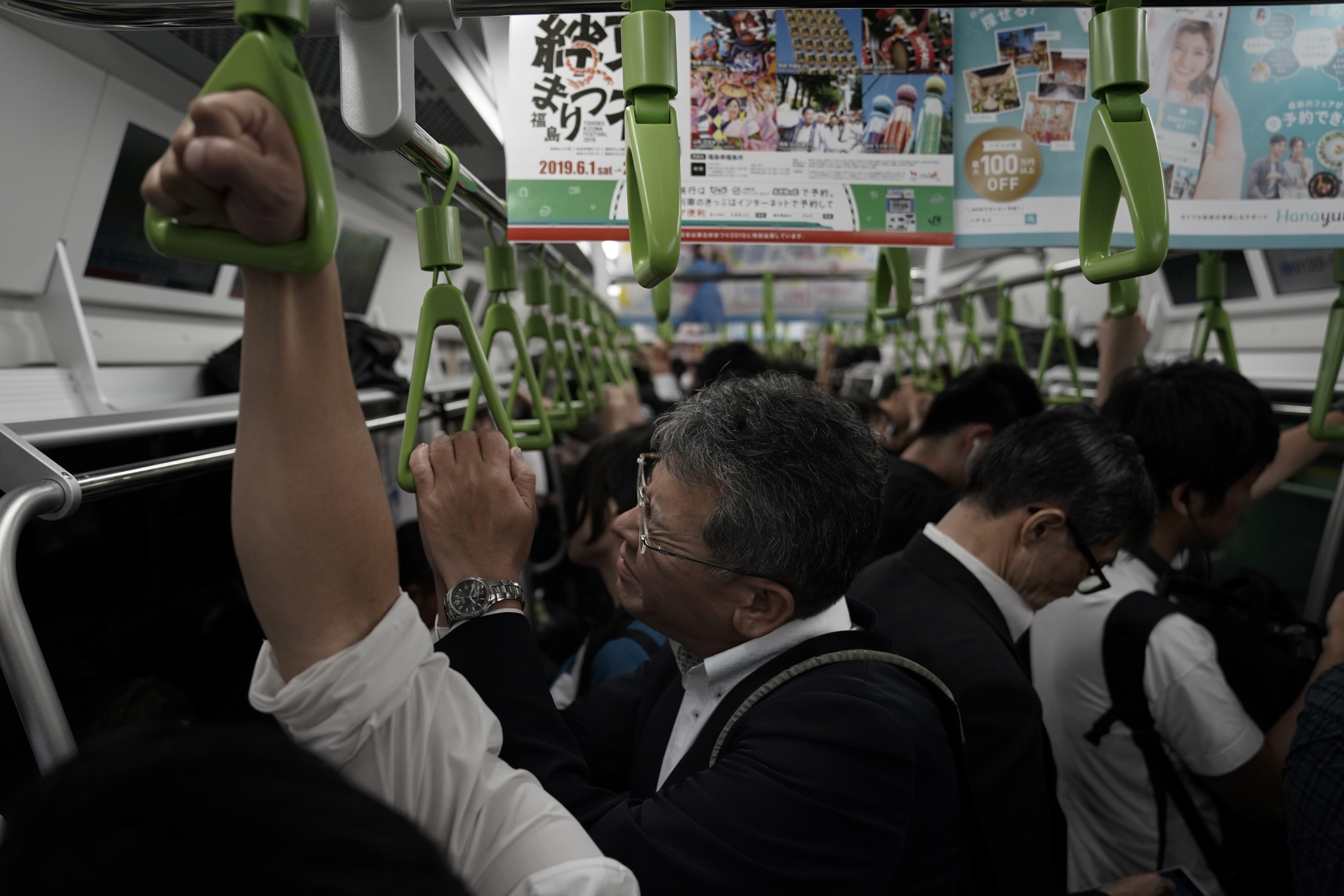In this Tuesday, May 21, 2019, photo, a man reacts in a packed Yamanote Line train during evening rush hours in Tokyo. Want to take a glimpse of daily life in downtown Tokyo? Take a ride on the Yamanote loop line. For most Tokyoites, the line means an incredibly punctual and efficient transportation system for commuting. For tourists, it offers a glimpse into the life of ordinary people living in the city.(AP Photo/Jae C. Hong)