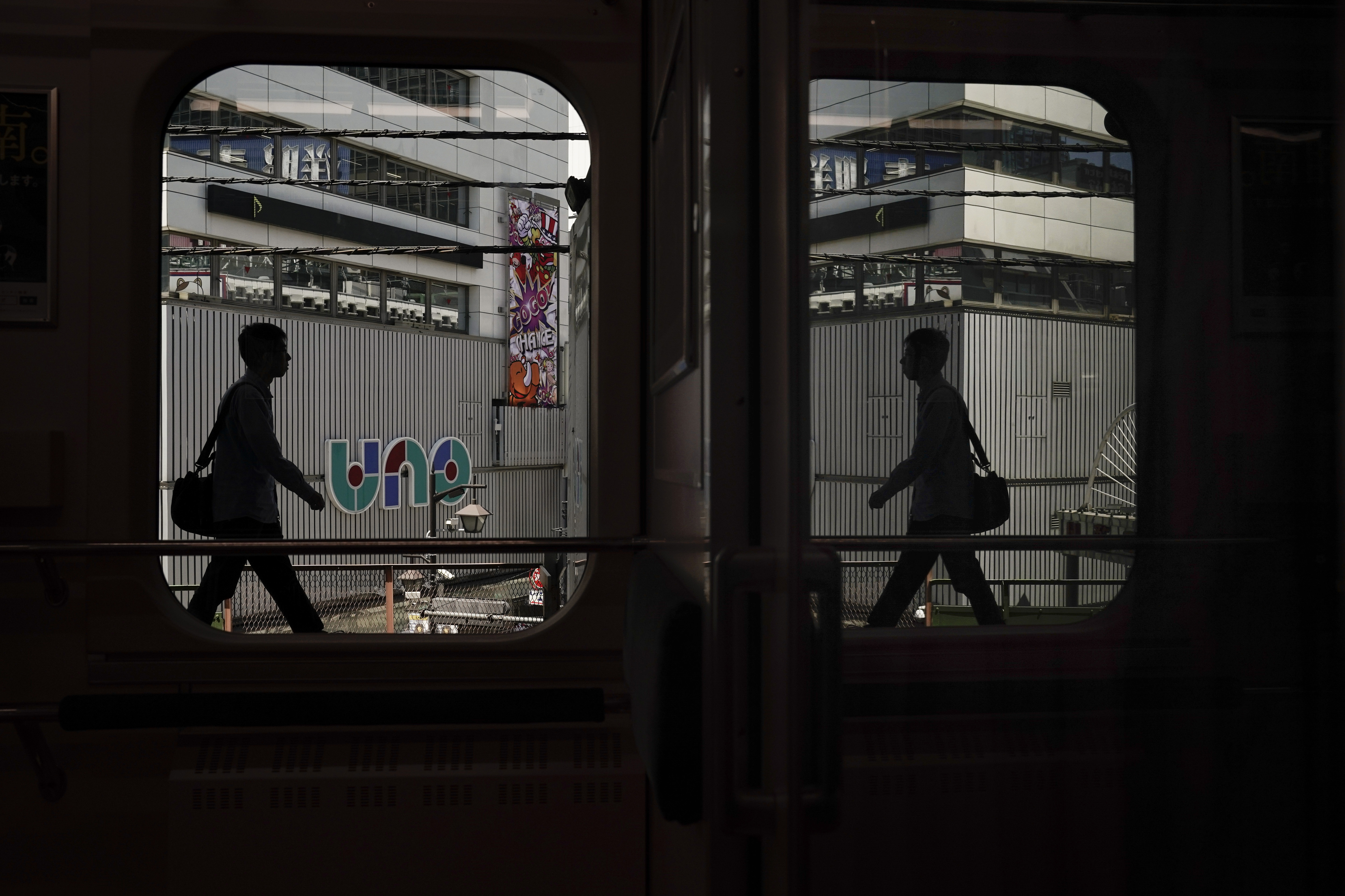 In this May 22, 2019, photo, a commuter is reflected in the window of a Yamanote Line train as he gets off at Shimbashi Station in Tokyo. Running above ground, views from wide windows on the train range from high-rises to local shopping arcade as the train covers different parts of the city. The line, according to company statistics, moves roughly 3 to 4 million people daily, more than the entire population of Jamaica. (AP Photo/Jae C. Hong)