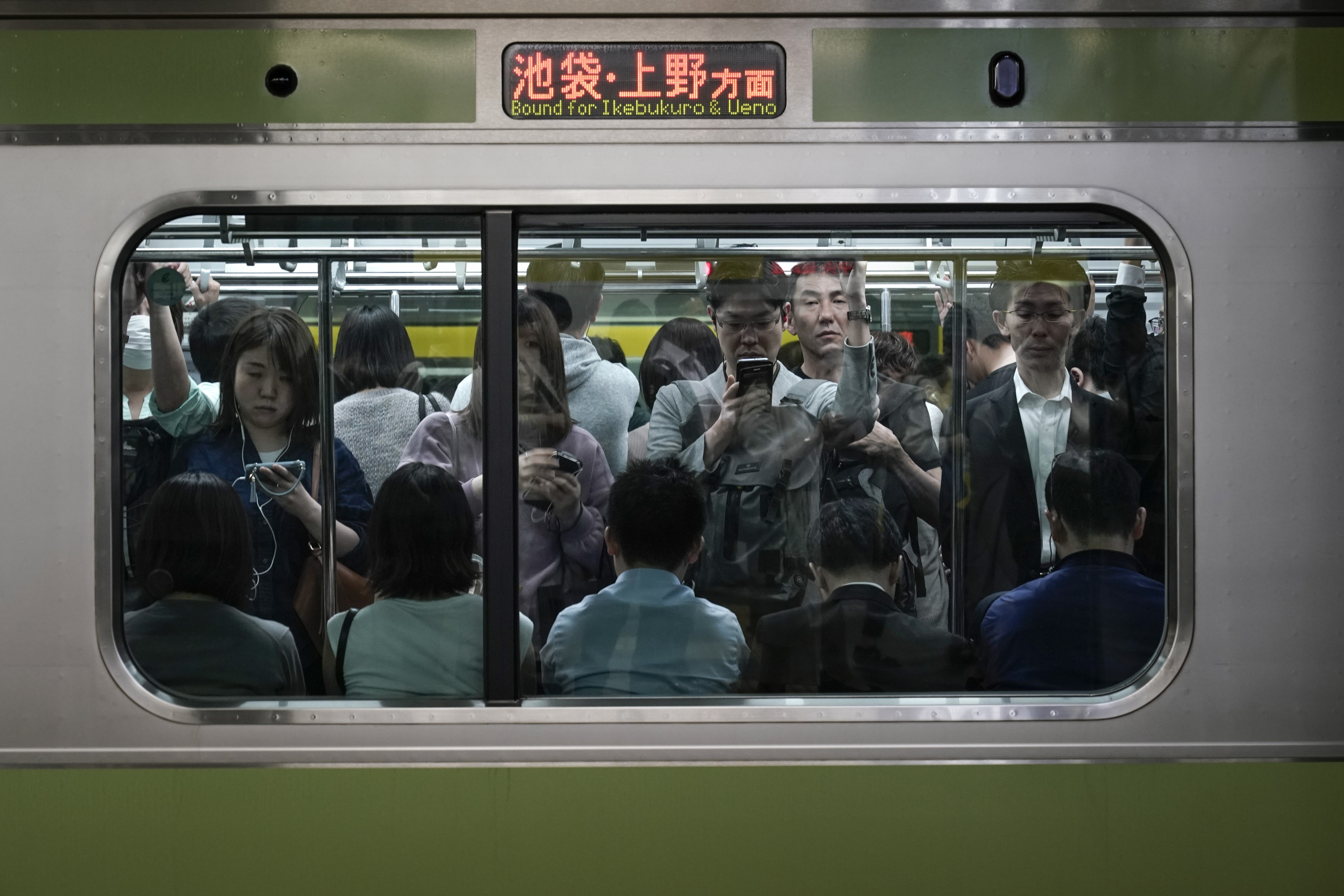 In this Saturday, May 25, 2019, photo, commuters stand in a packed Yamanote Line train while waiting for the train to depart at Shinjuku Station in Tokyo. Want to take a glimpse of daily life in downtown Tokyo? Take a ride on the Yamanote loop line. For most Tokyoites, the line means an incredibly punctual and efficient transportation system for commuting. For tourists, it offers a glimpse into the life of ordinary people living in the city. (AP Photo/Jae C. Hong)