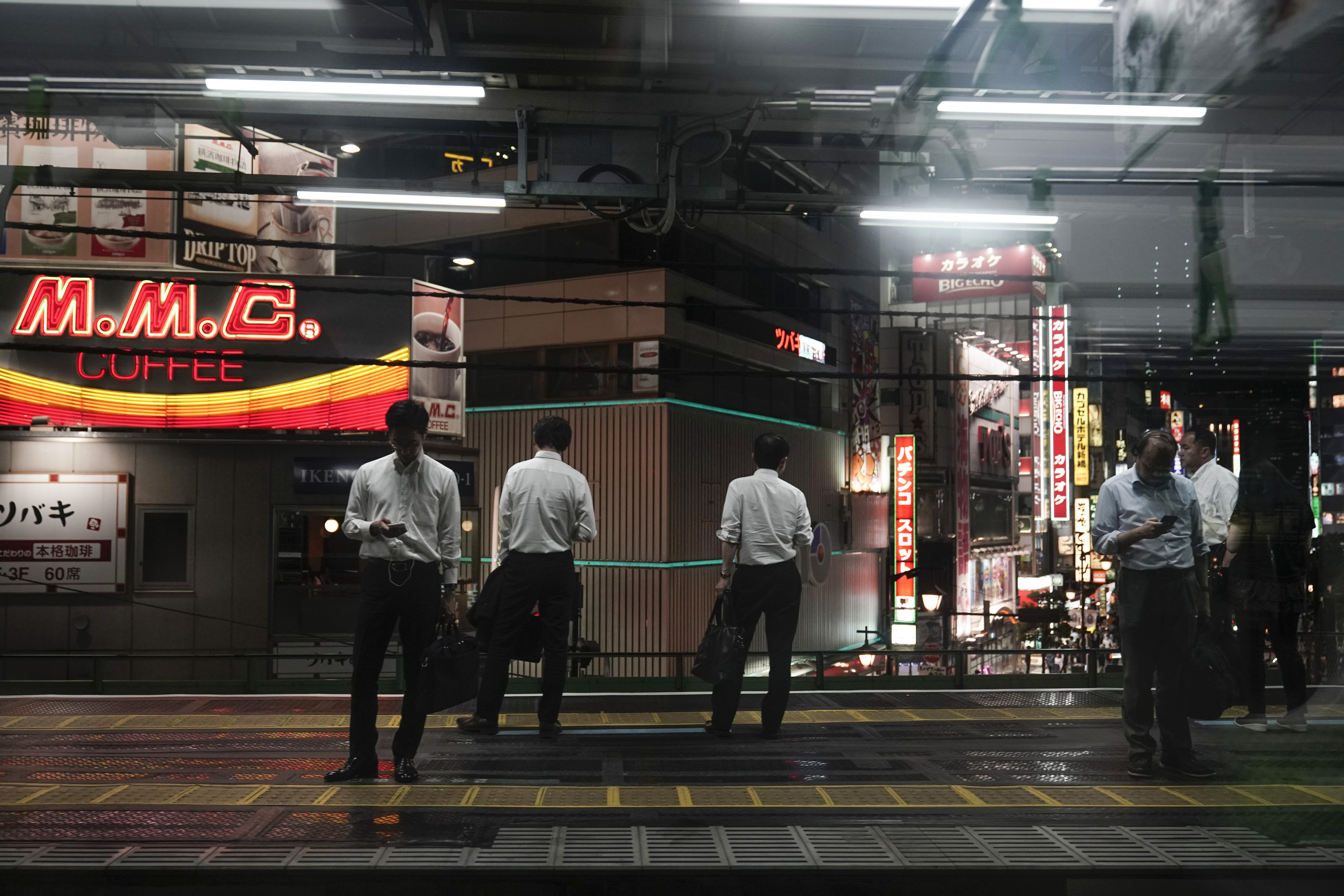 In this Friday, May 24, 2019, photo, commuters waiting for a train are seen through the window of a Yamanote Line train at Shimbashi Station in Tokyo. Running above ground, views from wide windows on the train range from high-rises to local shopping arcade as the train covers different parts of the city. The line, according to company statistics, moves roughly 3 to 4 million people daily, more than the entire population of Jamaica. (AP Photo/Jae C. Hong)