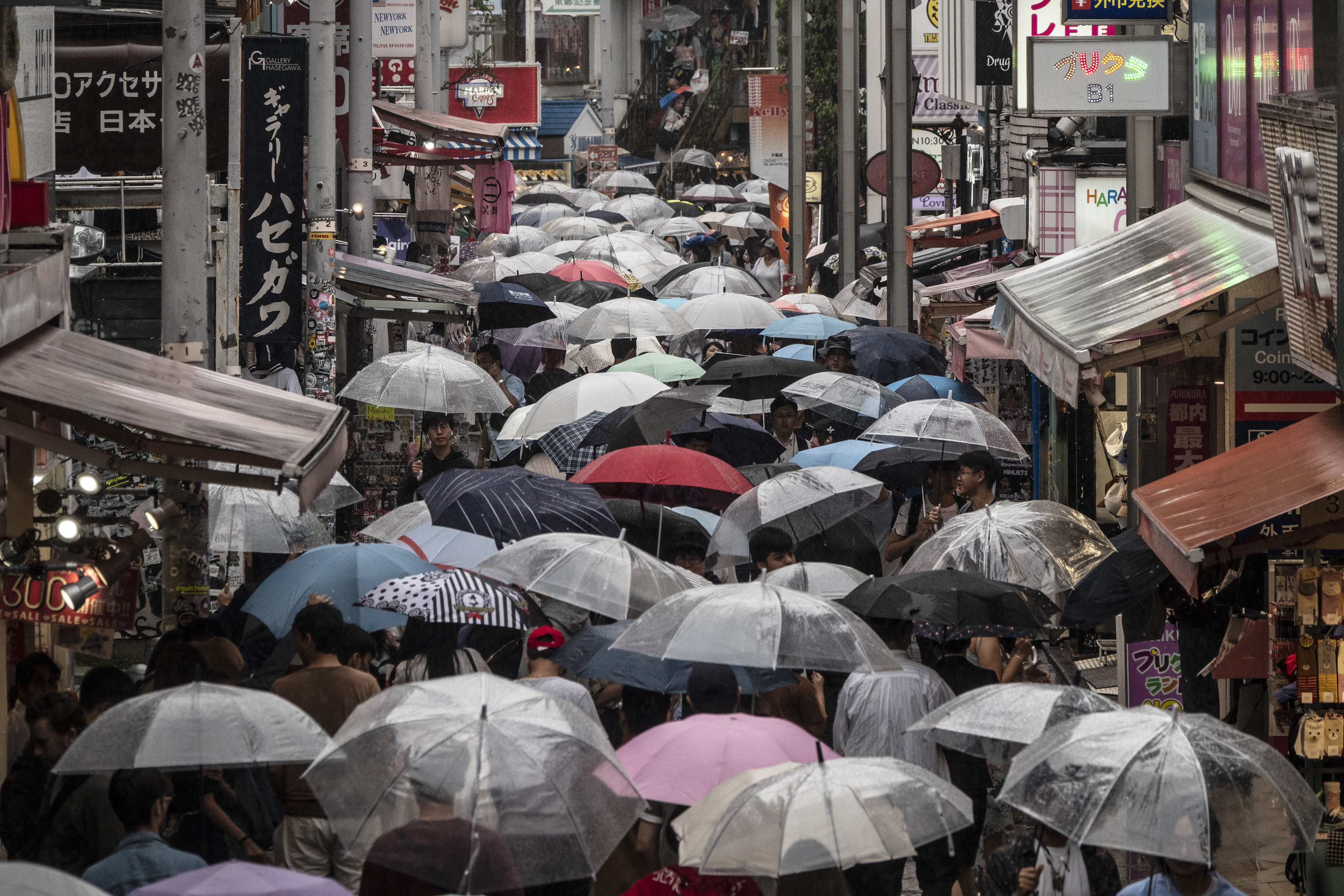 Shoppers with umbrellas walk along the Takeshita Street Friday, June 7, 2019, in the Harajuku district of Tokyo. Harajuku is one of the most popular shopping neighborhoods in Tokyo. (AP Photo/Jae C. Hong)