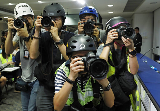 Press photographers wearing helmets for protection in the clashes seen in recent protests, photograph a press conference by Commissioner of Police Stephen Lo in Hong Kong, Thursday, June 13, 2019. (AP Photo/Vincent Yu)