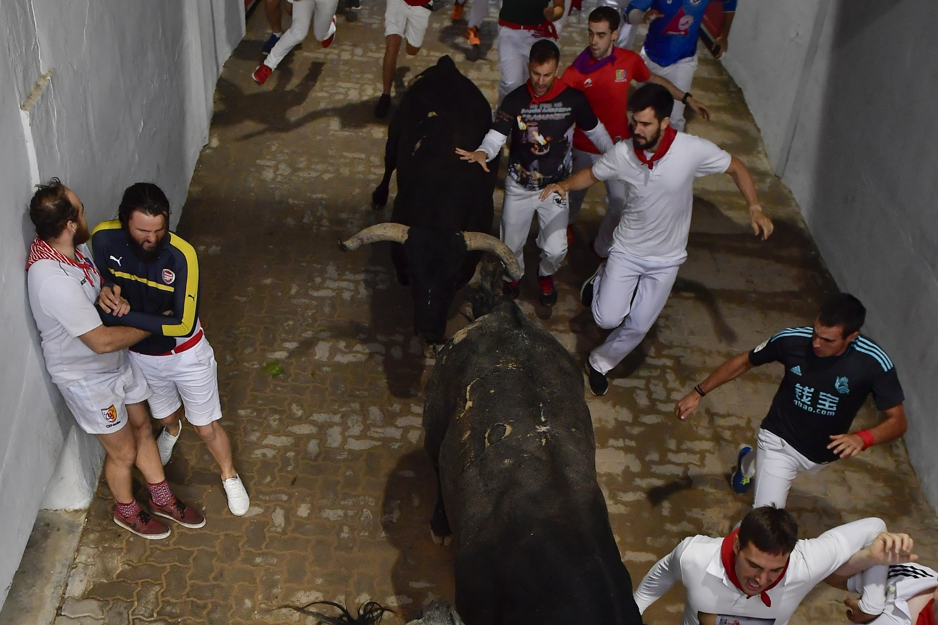 Revellers run next to fighting bulls during the running of the bulls at the San Fermin Festival, in Pamplona, northern Spain, Sunday, July 14, 2019. The San Fermin fiesta made internationally famous by Ernest Hemingway in his novel 