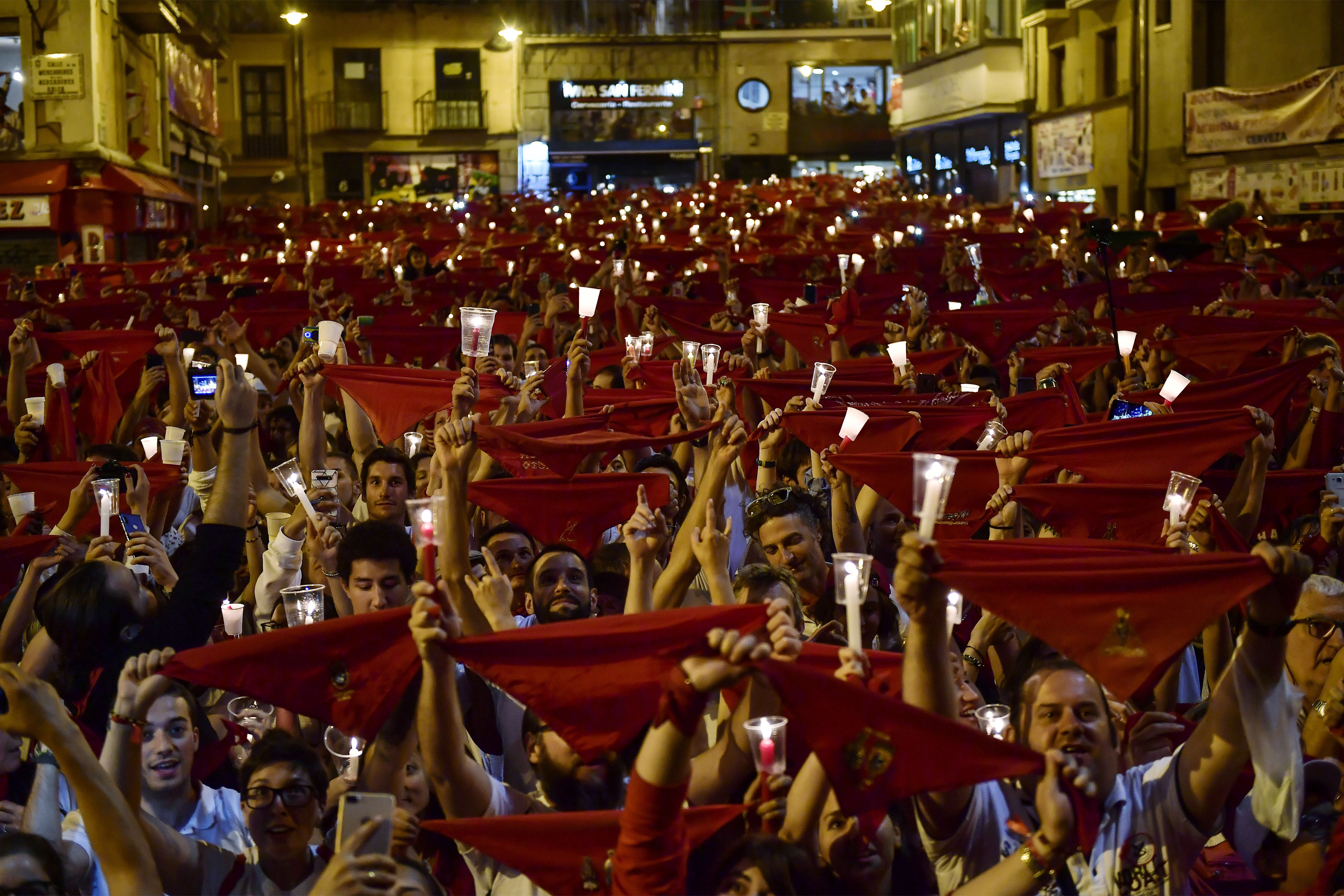 Revelers hold candles and red kerchief after singing a song ''Pobre de Mi'' to close nine days of the running of the bulls, music and dance at the San Fermin Festival, in Pamplona, northern Spain, Monday, July 15, 2019. (AP Photo/Alvaro Barrientos)