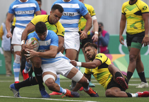 Gaston Revol of Argentina, center, is tackled by Mason Caton-Brown, right, and Conan Osborne of Jamaica, left, during rugby seven match at the Pan Am Games in Lima, Peru, Friday, July 26, 2019. Argentina won the match 52-0. (AP Photo/Juan Karita)