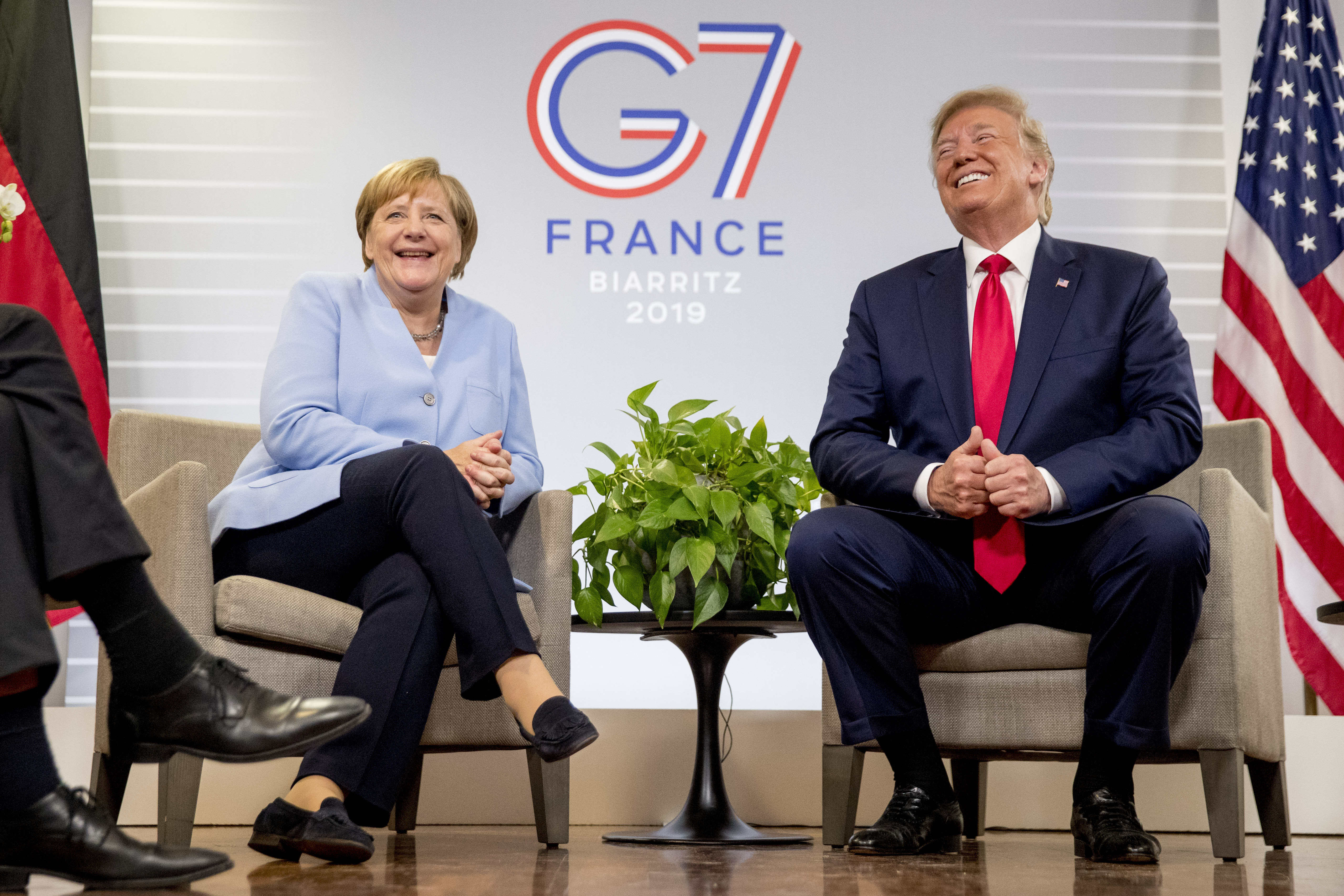 U.S. President Donald Trump and German Chancellor Angela Merkel laugh during a bilateral meeting at the G-7 summit in Biarritz, France, Monday, Aug. 26, 2019. (AP Photo/Andrew Harnik)