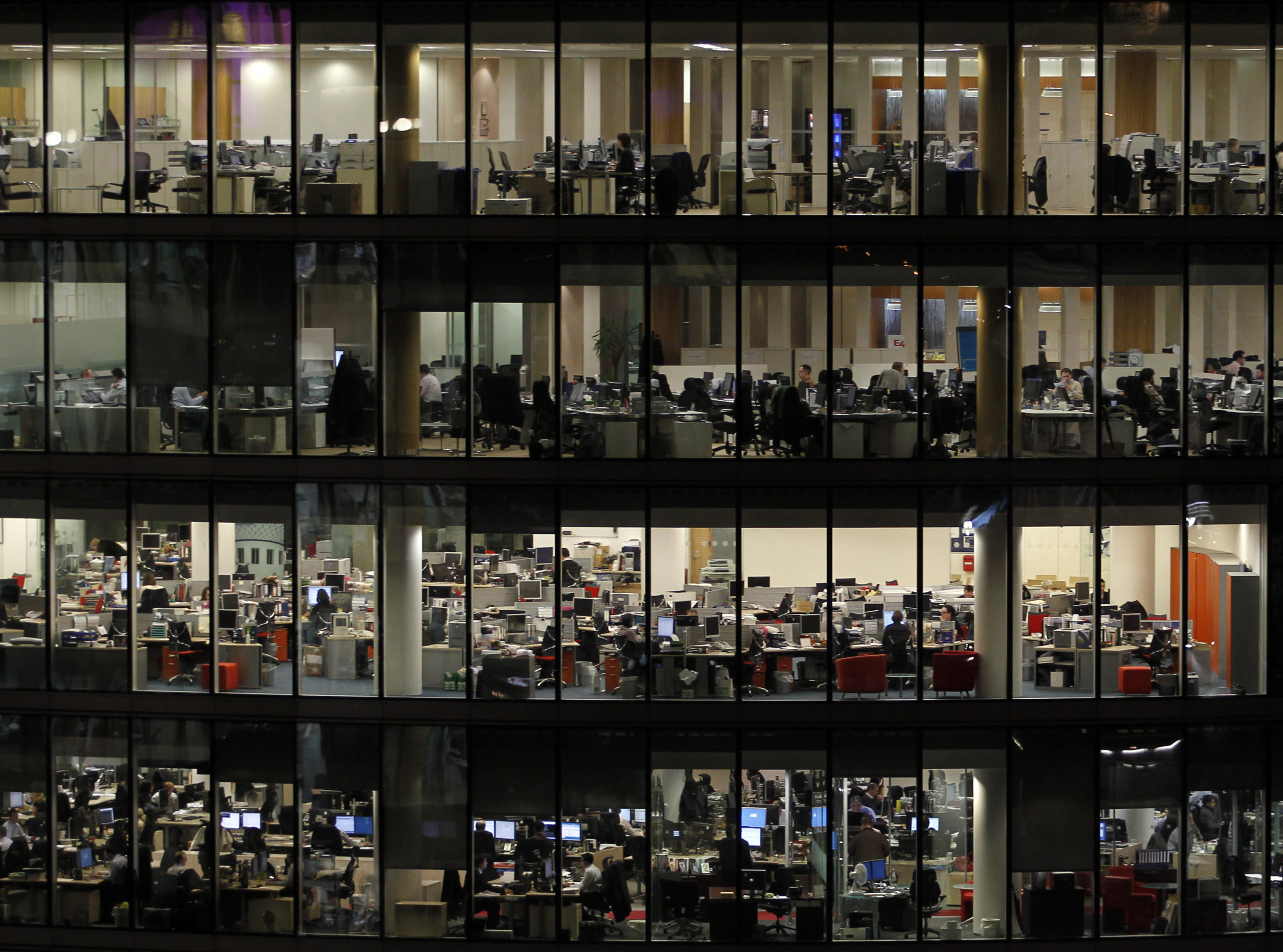 People are seen through windows as they work in a office building on the south bank of the River Thames, next door to City Hall,  in central London, Monday, Jan. 25, 2010.  (AP Photo/Matt Dunham)