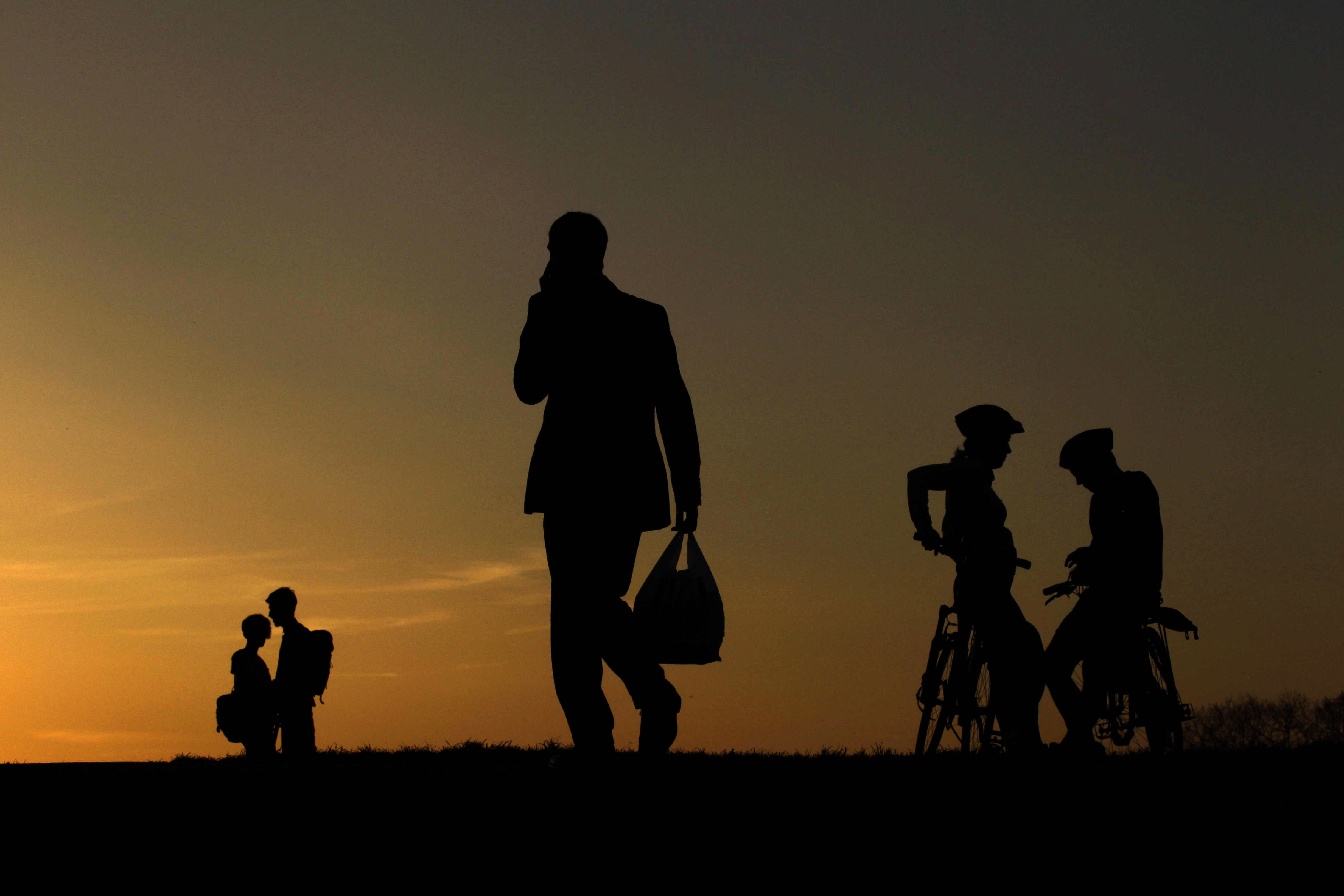 People are silhouetted against the sky from the setting sun on Parliament Hill in Hampstead Heath, London, Friday, April 8, 2011. (AP Photo/Matt Dunham)