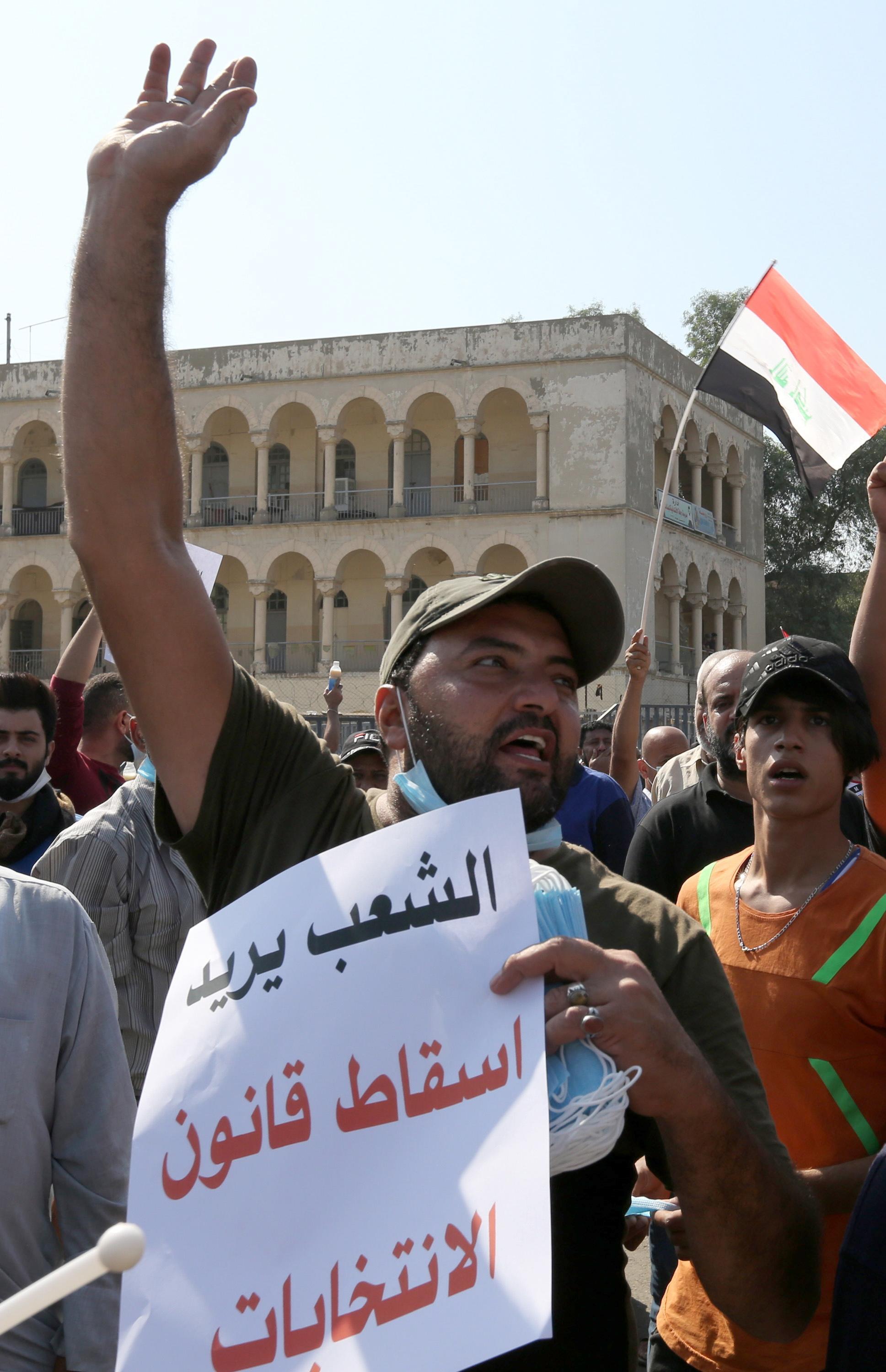 epa07950893 Iraqi protesters chant slogans and carry placards reading in Arabic 'The people want to bring down the election law' during protests at Tahrir square in central Baghdad, Iraq, 26 October 2019. According to media reports, at least 40 people died during violence between security forces and people protesting against the government in Baghdad and southern Iraqi cities.  EPA/AHMED JALIL