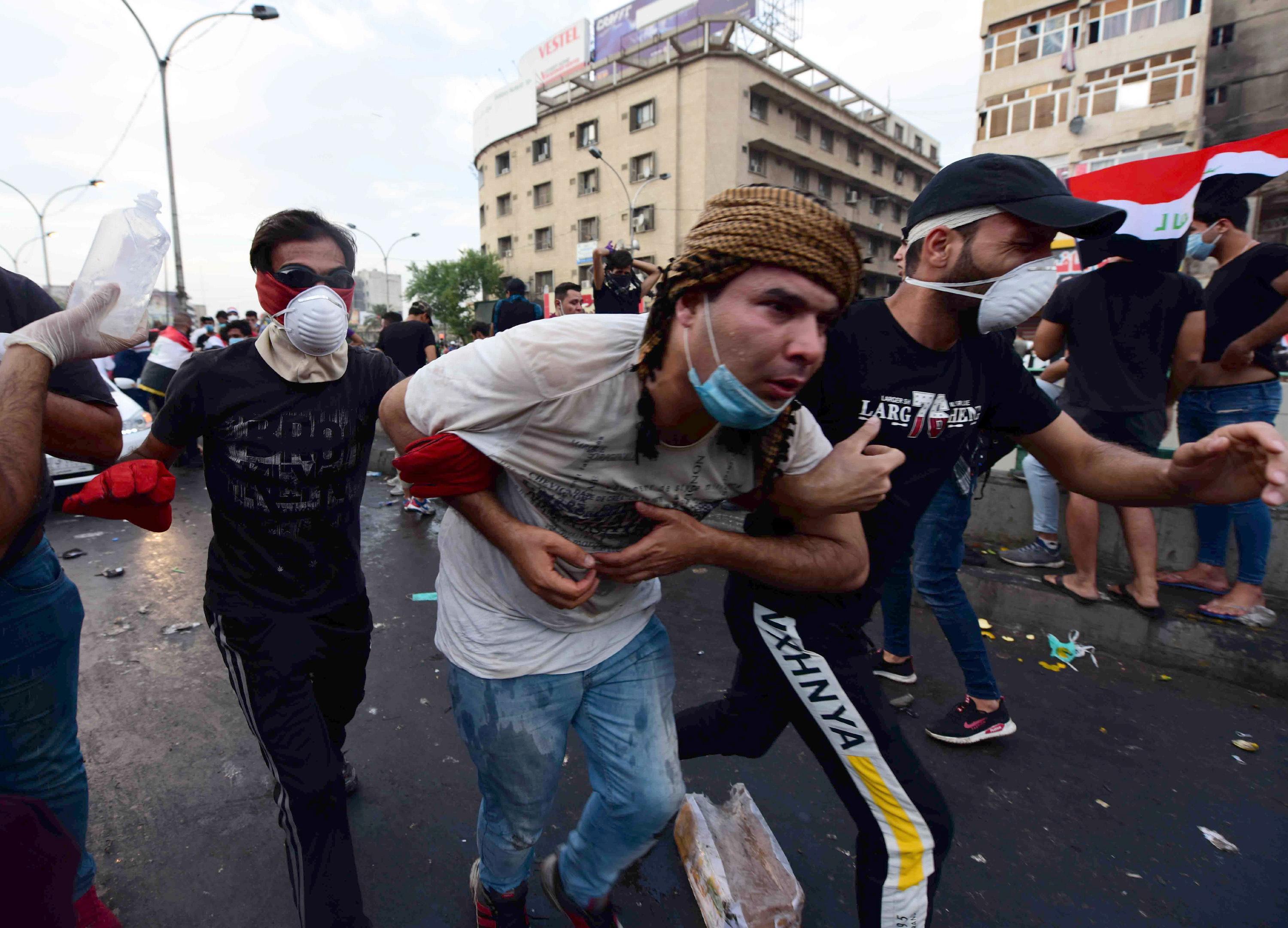 epa07954348 Iraqi protesters help a man who was injured during clashes with Iraqi riot forces following a demonstration at al-Tahrir square, central Baghdad, Iraq, 27 October 2019. According to media reports, at least 63 people died during three days of violent clashes between security forces and people protesting against the government in Baghdad and southern Iraqi cities.  EPA/MURTAJA LATEEF