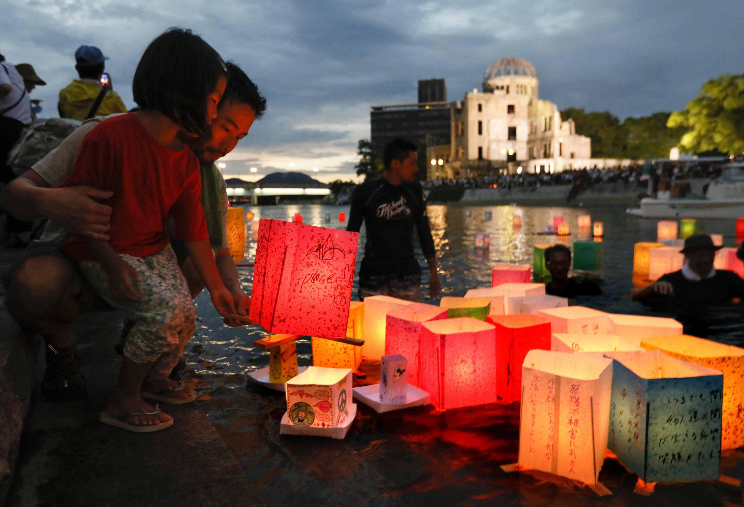 epa06128342 A little girl assisted by her father floats a paper lantern to comfort souls of victims of the 06 August 1945 atomic bombing, at Hiroshima Peace Memorial Park in Hiroshima, western Japan, 06 August 2017. Hiroshima marked the 72nd anniversary of the atomic bombing on 06 August 2017. The Atomic Bomb Dome is seen in the rear.  EPA/KIMIMASA MAYAMA
