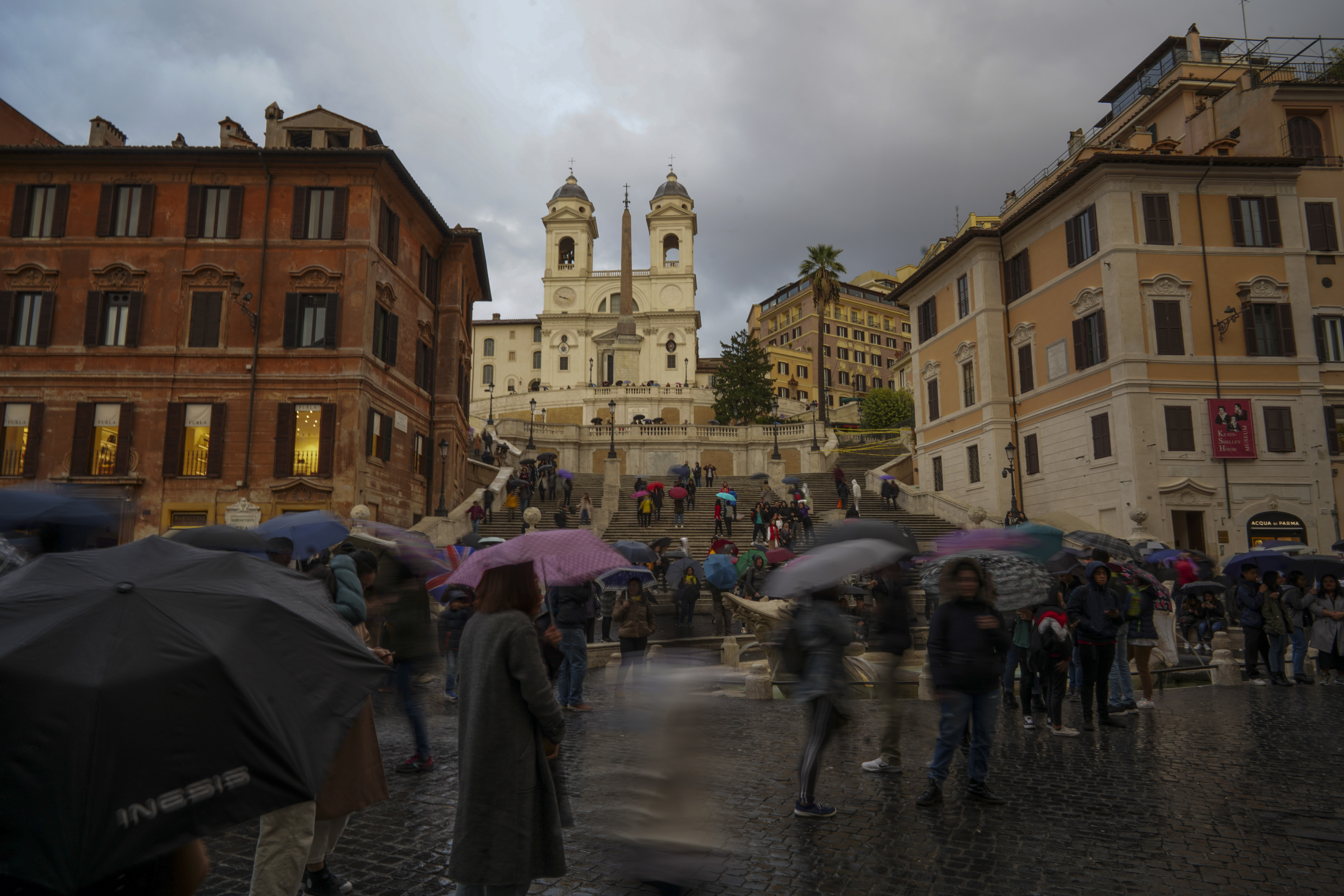 Tourists hold umbrellas as they walk past Rome's historical Spanish Steps, Thursday, Nov. 14, 2019. (AP Photo/Andrew Medichini)