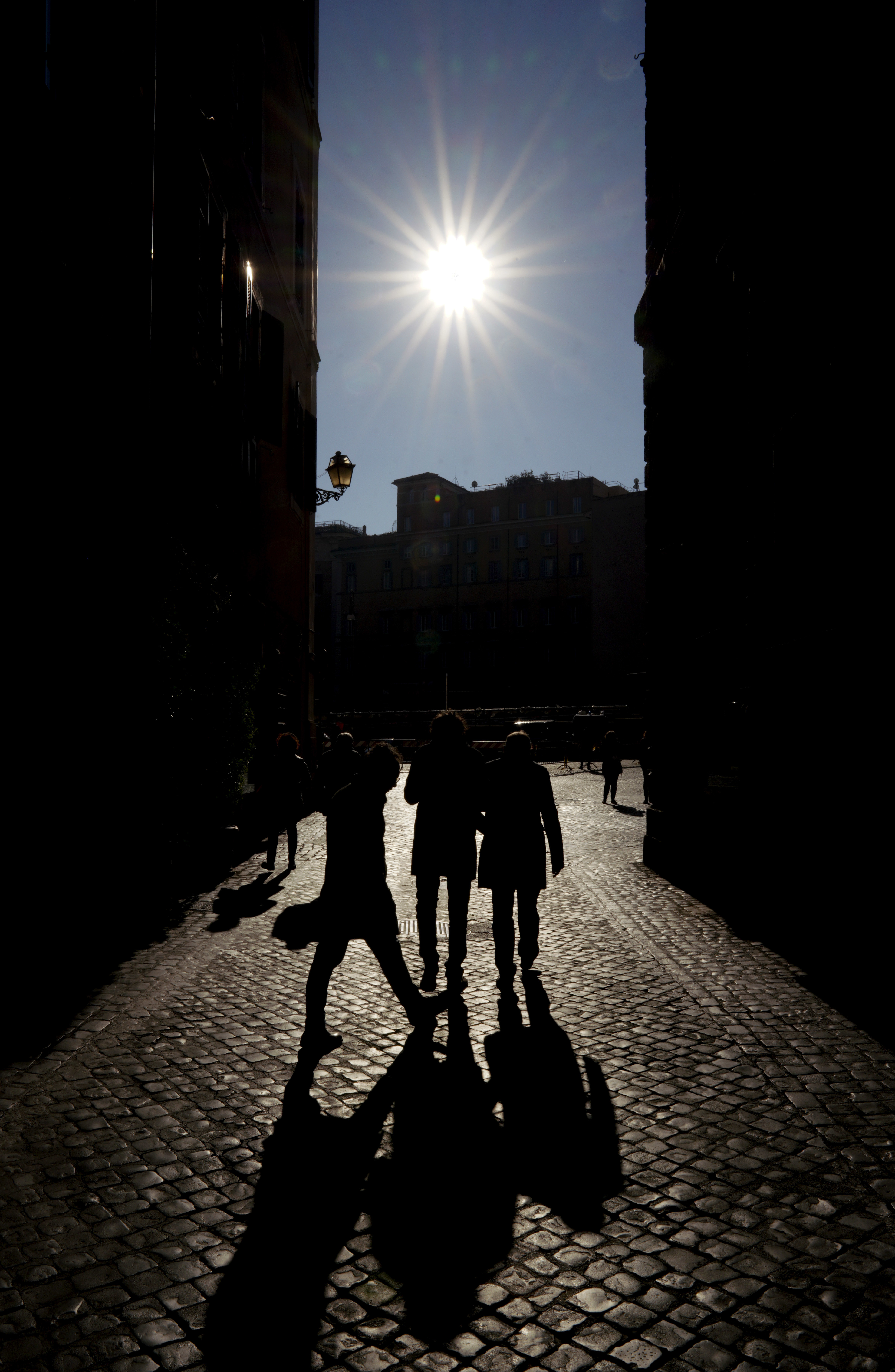 People are silhouetted as they walk along an alley in downtown Rome, Monday, Jan. 7, 2019. (AP Photo/Andrew Medichini)