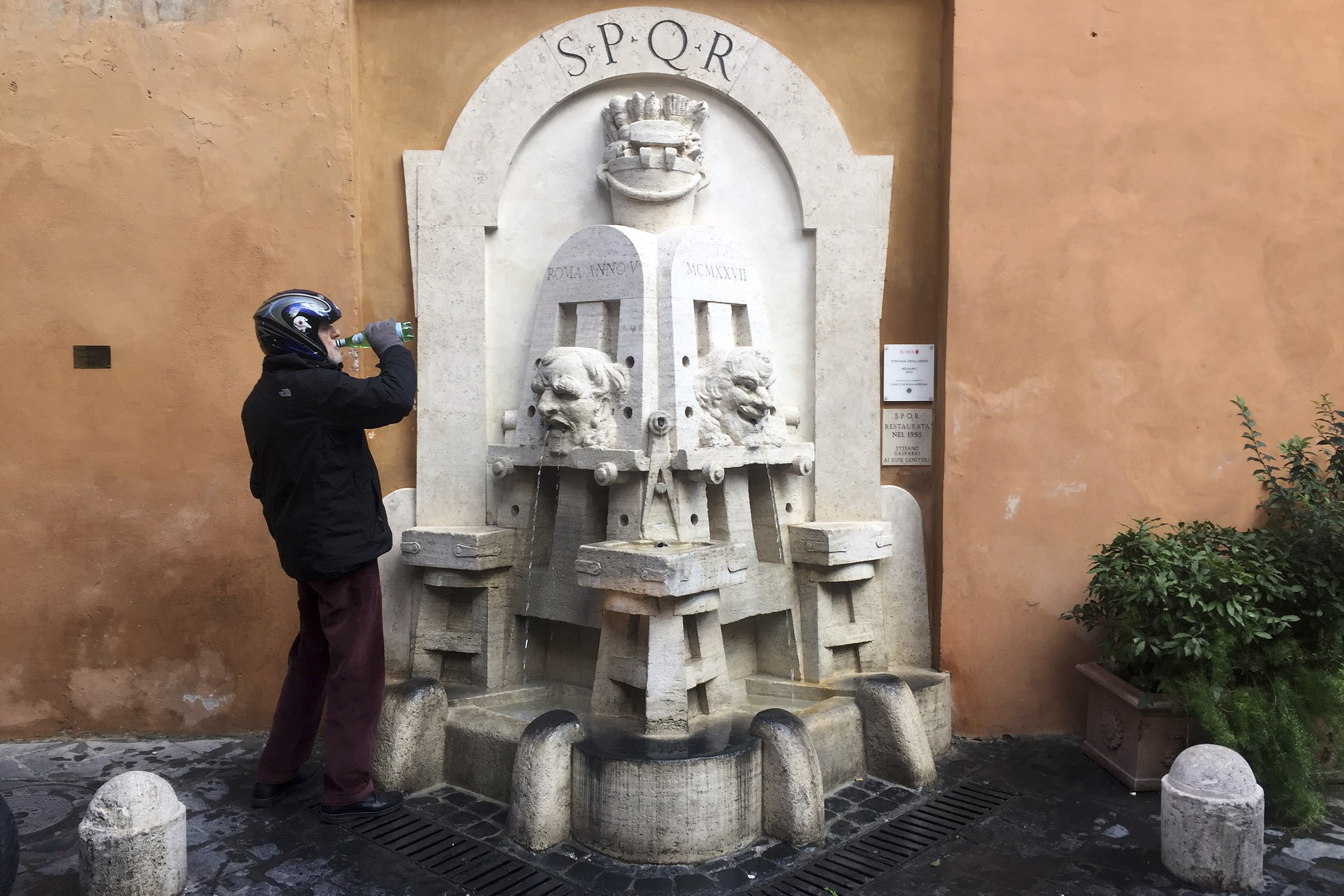 In this picture taken Thursday, Nov. 22, 2018, a man drinks water he collected from the 1925 Artists fountain by Italian sculptor Pietro Lombardi in Rome's Via Margutta. (AP Photo/Gregorio Borgia)
