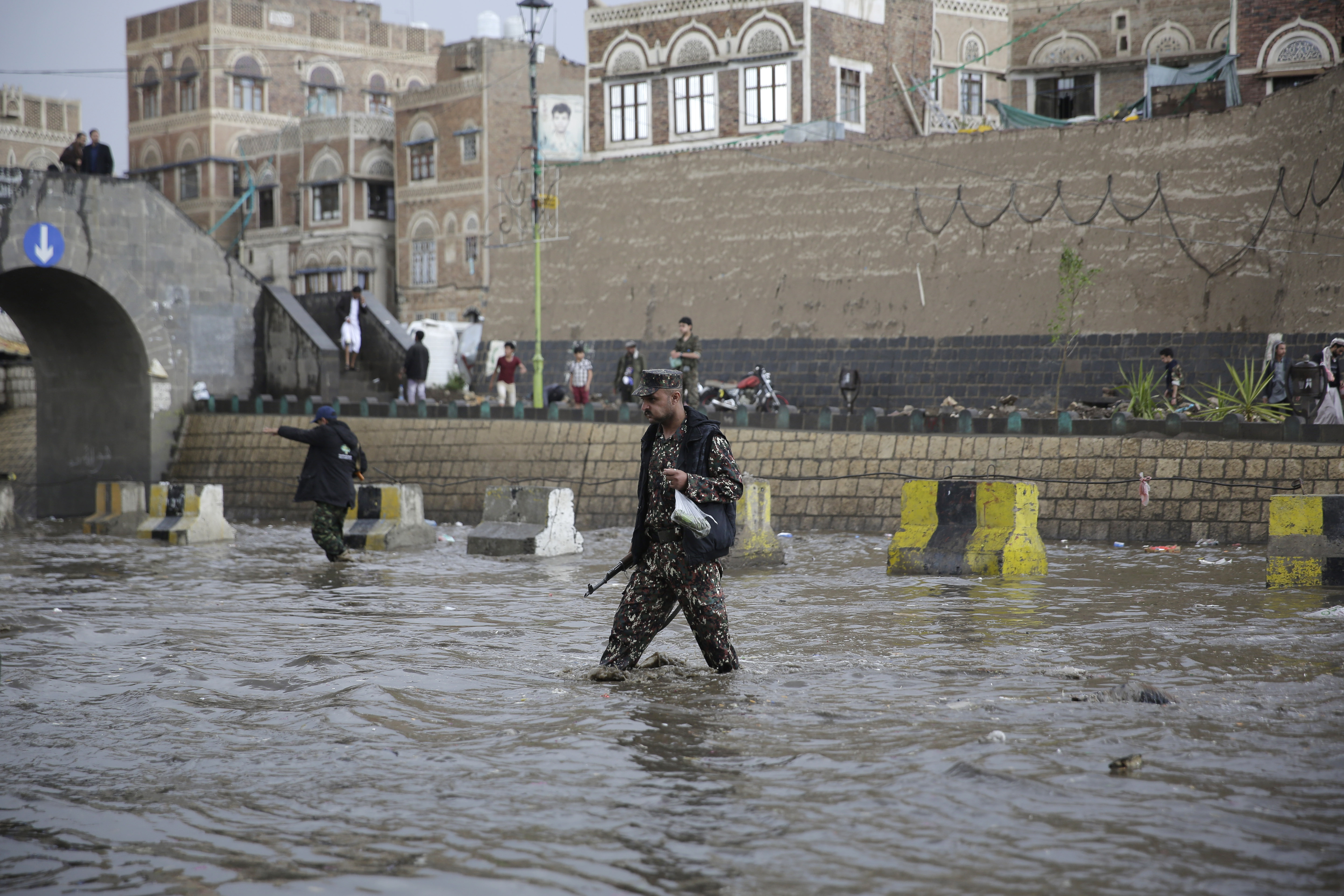 A Houthi militant cross a flooded street as he guards a street leading to a protest against the U.S. airstrike in Iraq that killed of Iraqi militia commander Abu Mahdi al-Muhandis and Iranian military commander Qassem Soleimani, in Sanaa, Yemen, Monday, Jan. 6, 2020. (AP Photo/Hani Mohammed)