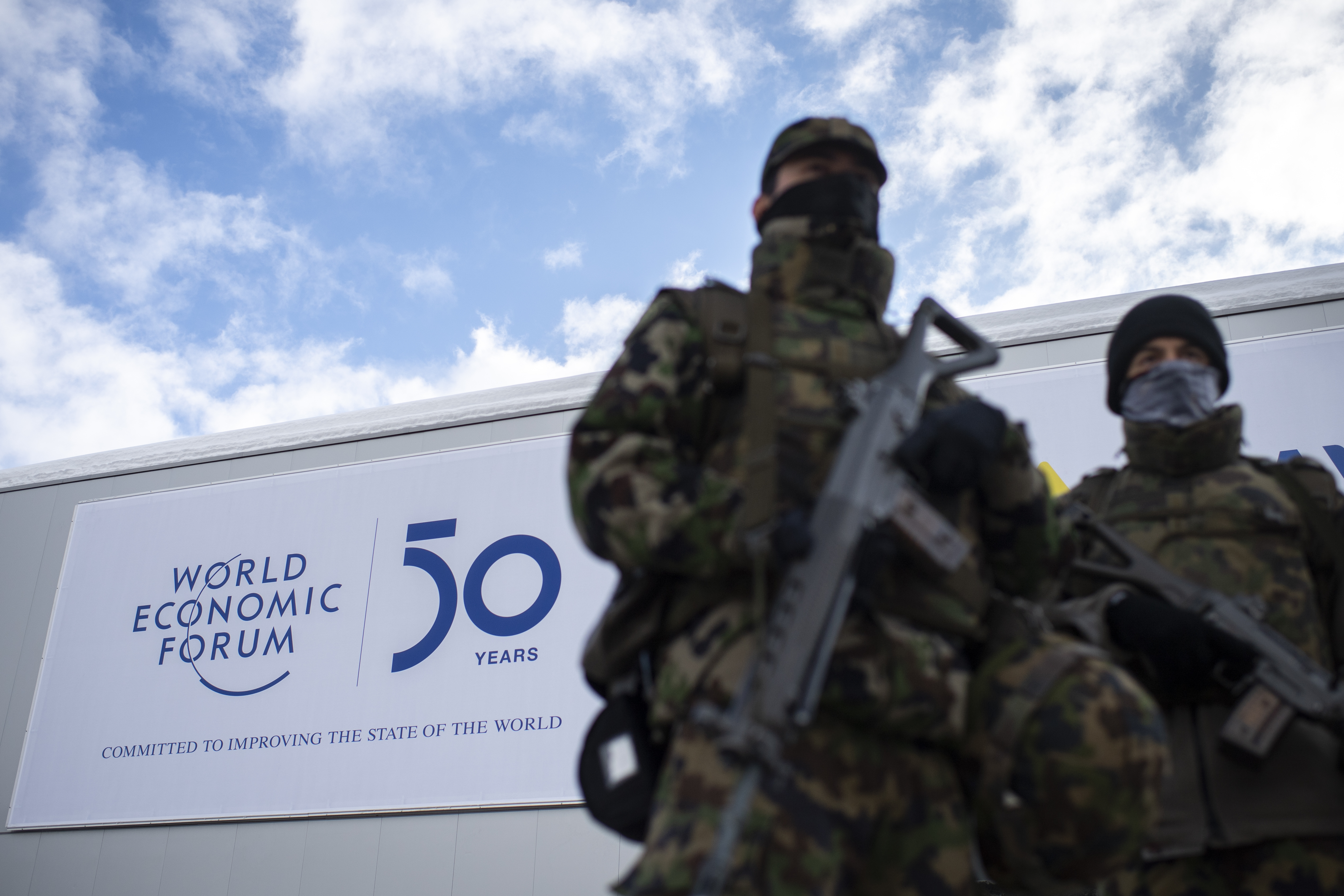 The logo of the WEF is seen behind soldiers of the Swiss Army on guard outside the congress center prior the 50th annual meeting of the World Economic Forum, WEF, in Davos, Switzerland, Sunday, Jan. 19, 2020.  (Gian Ehrenzeller/Keystone via AP)