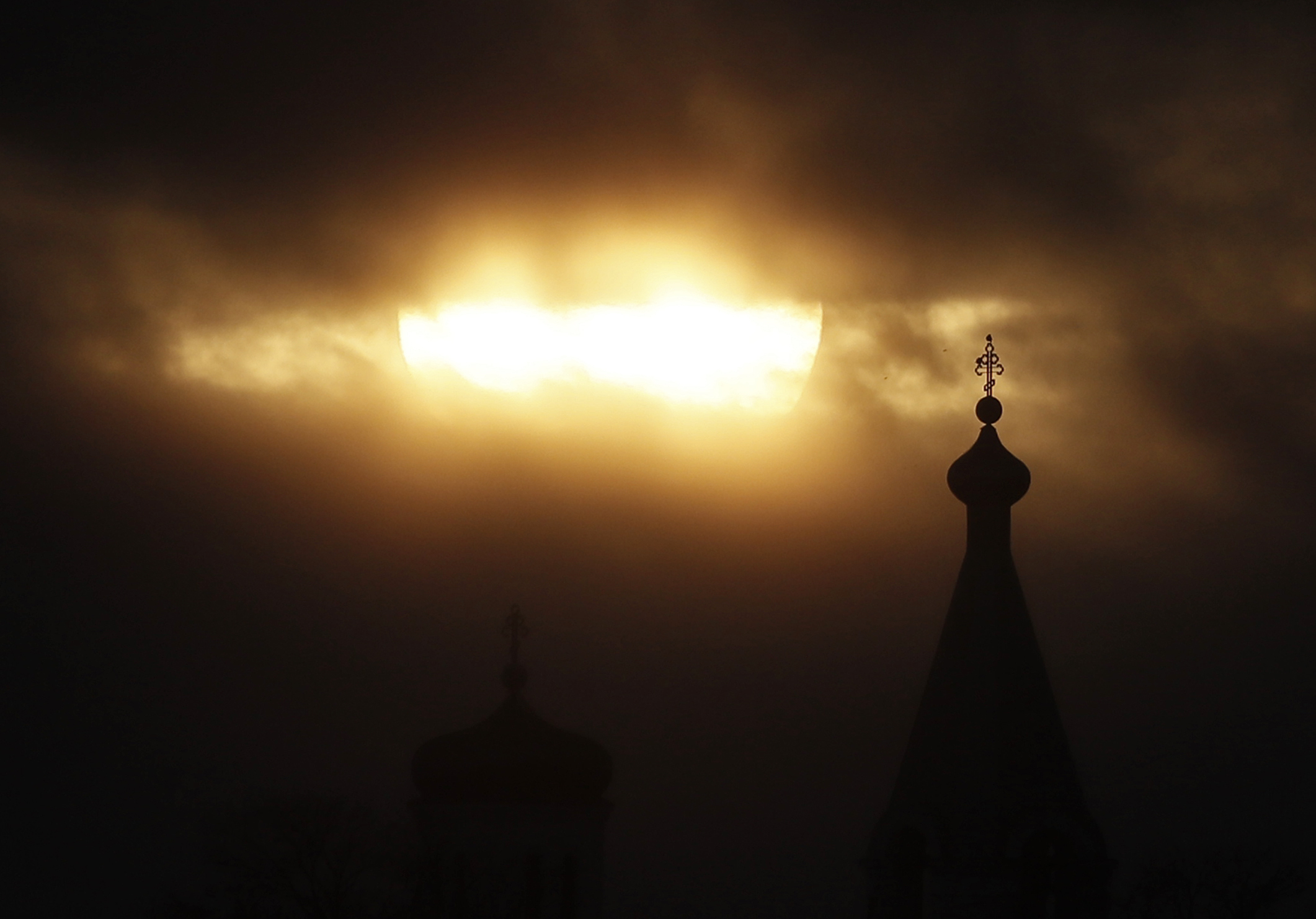 The sun sets in the clouds over an Orthodox church near the city of Volkhov, 130 km (80 miles) east of St.Petersburg, Russia, Saturday, Jan. 4, 2020. (AP Photo/Dmitri Lovetsky)