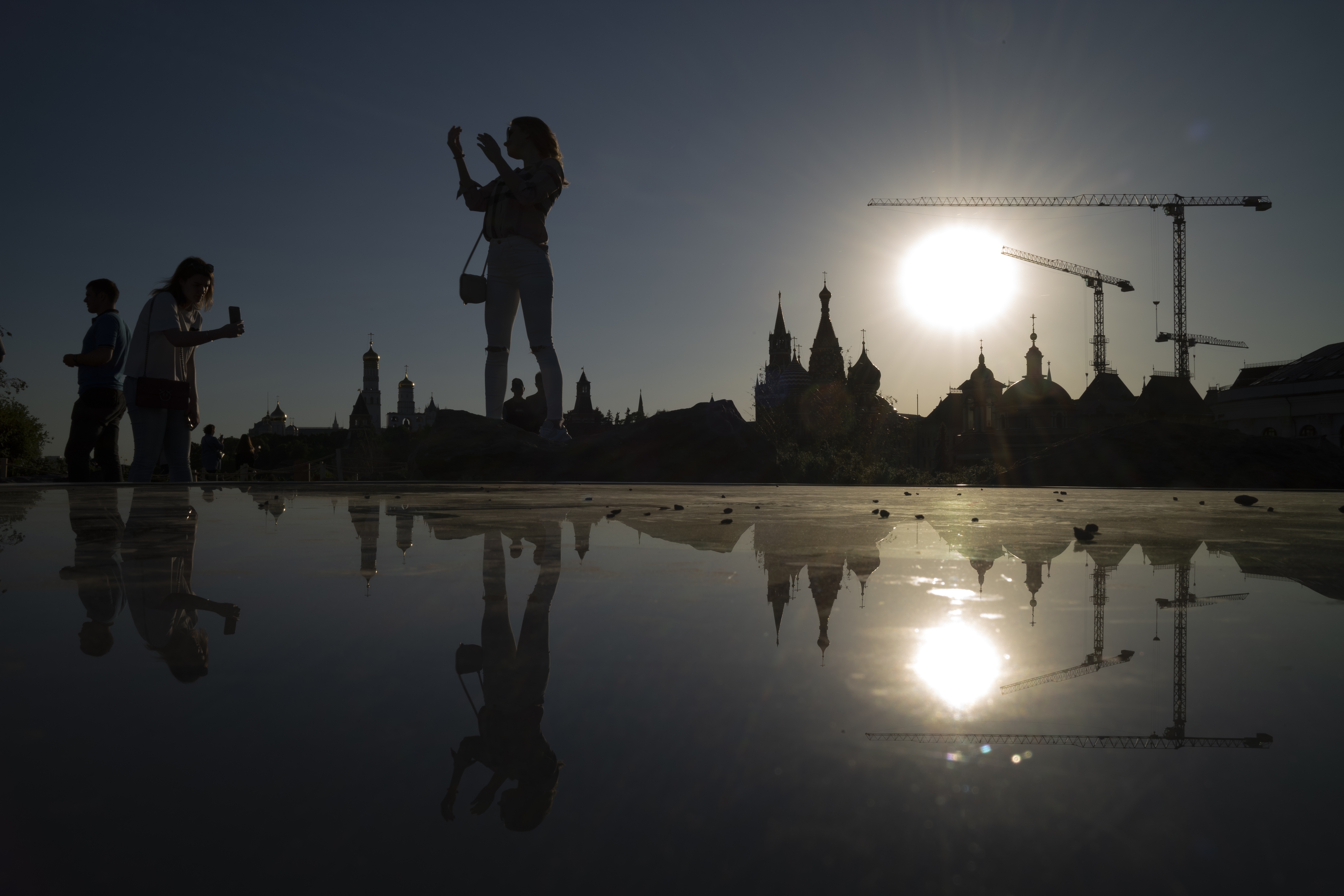A woman poses for a photo at Zaryadye Park with the Kremlin in the background during a sunset in Moscow, Russia, Saturday, May 18, 2019. (AP Photo/Alexander Zemlianichenko)