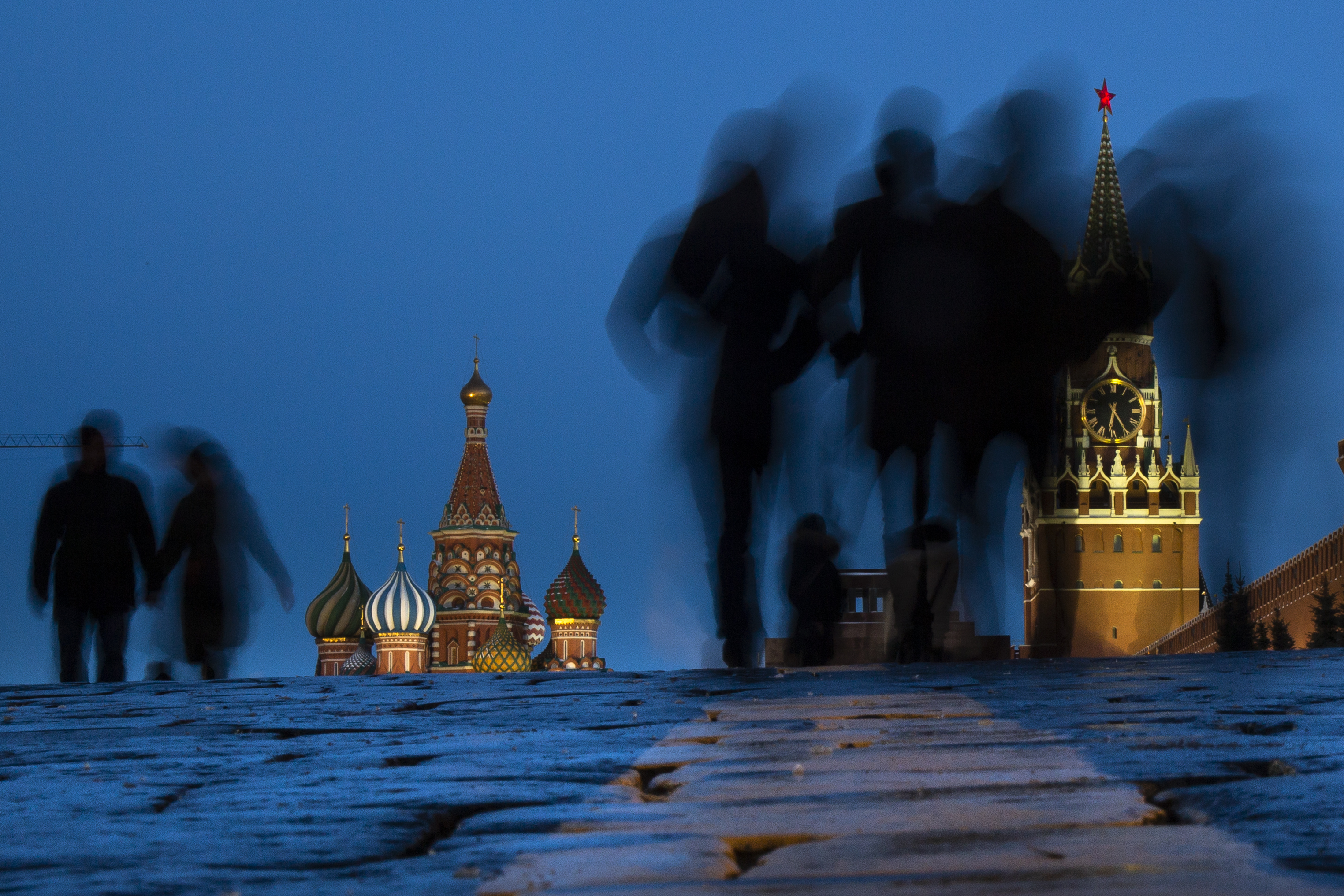 People walk through Red Square after sunset in Moscow, Russia, Sunday, March 3, 2019, with the St. Basil's background left, and the Spasskaya Tower, right, in the background. (AP Photo/Alexander Zemlianichenko)