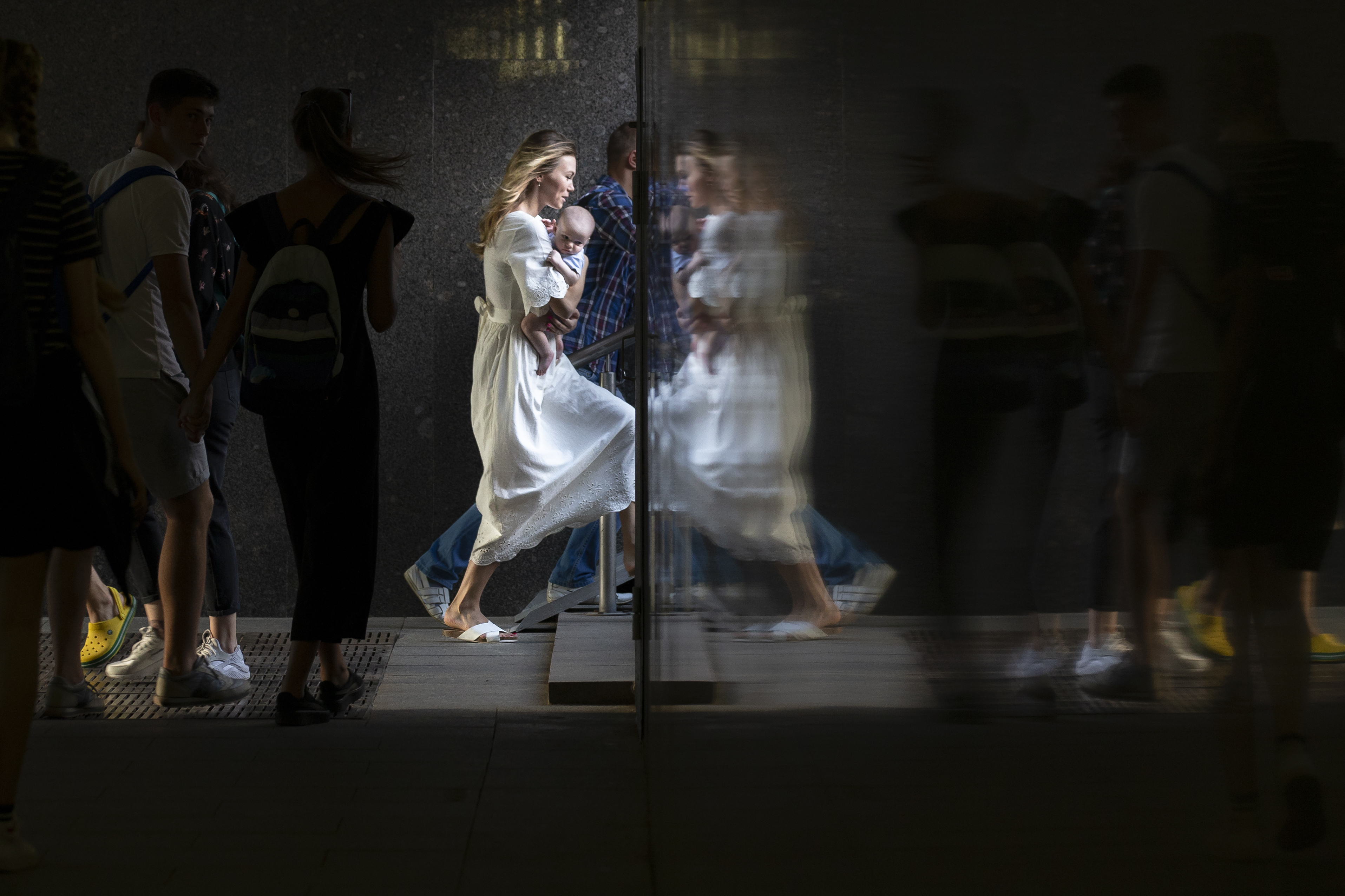 A woman carrying her child is reflected in a wall as she steps up in a subway in Moscow, Russia, Wednesday, Aug. 29, 2018. (AP Photo/Alexander Zemlianichenko)