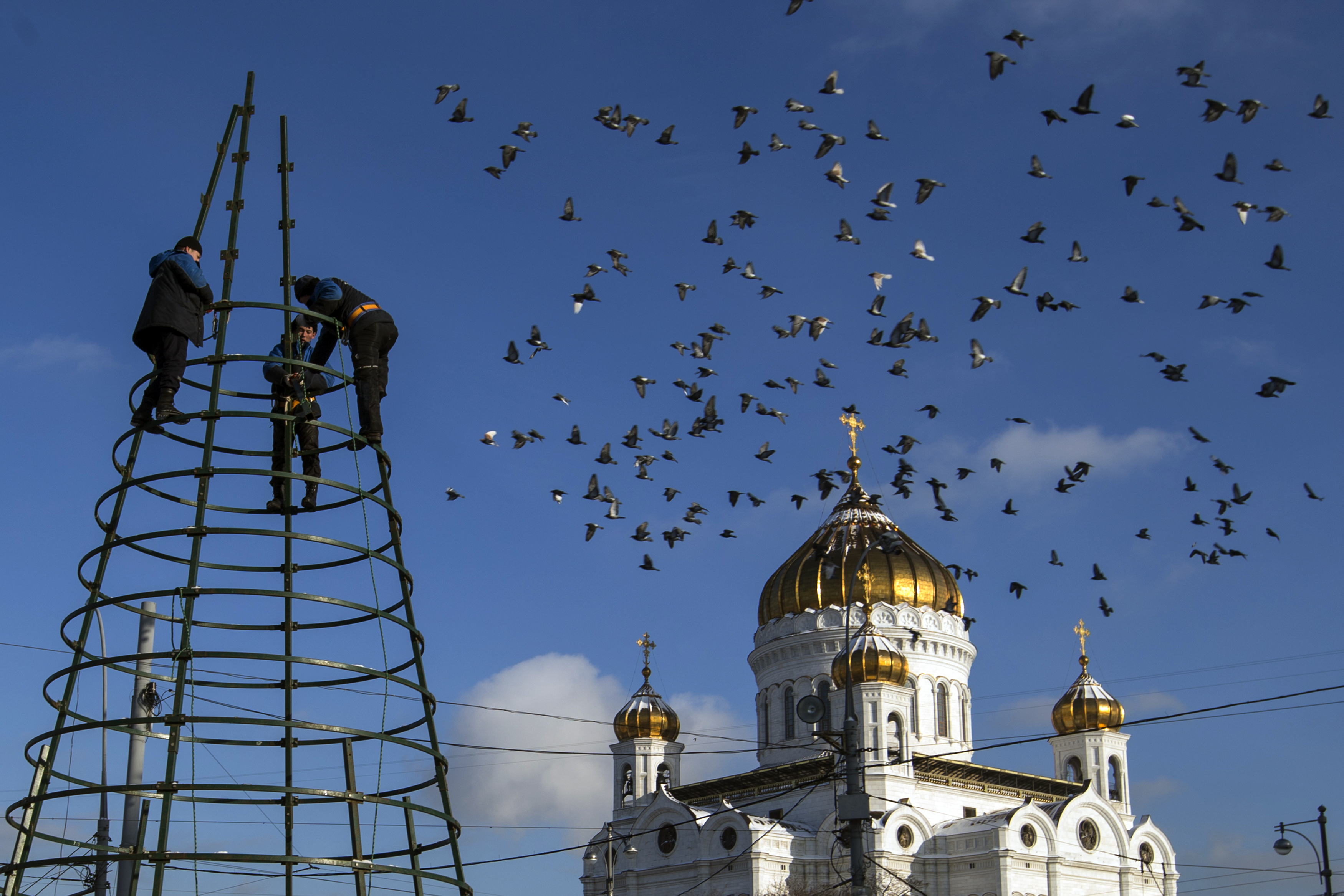 Municipal workers disassemble Christmas decorations in front of Christ the Savior Cathedral in Moscow, Thursday, Jan. 21, 2016. (AP Photo/Pavel Golovkin)