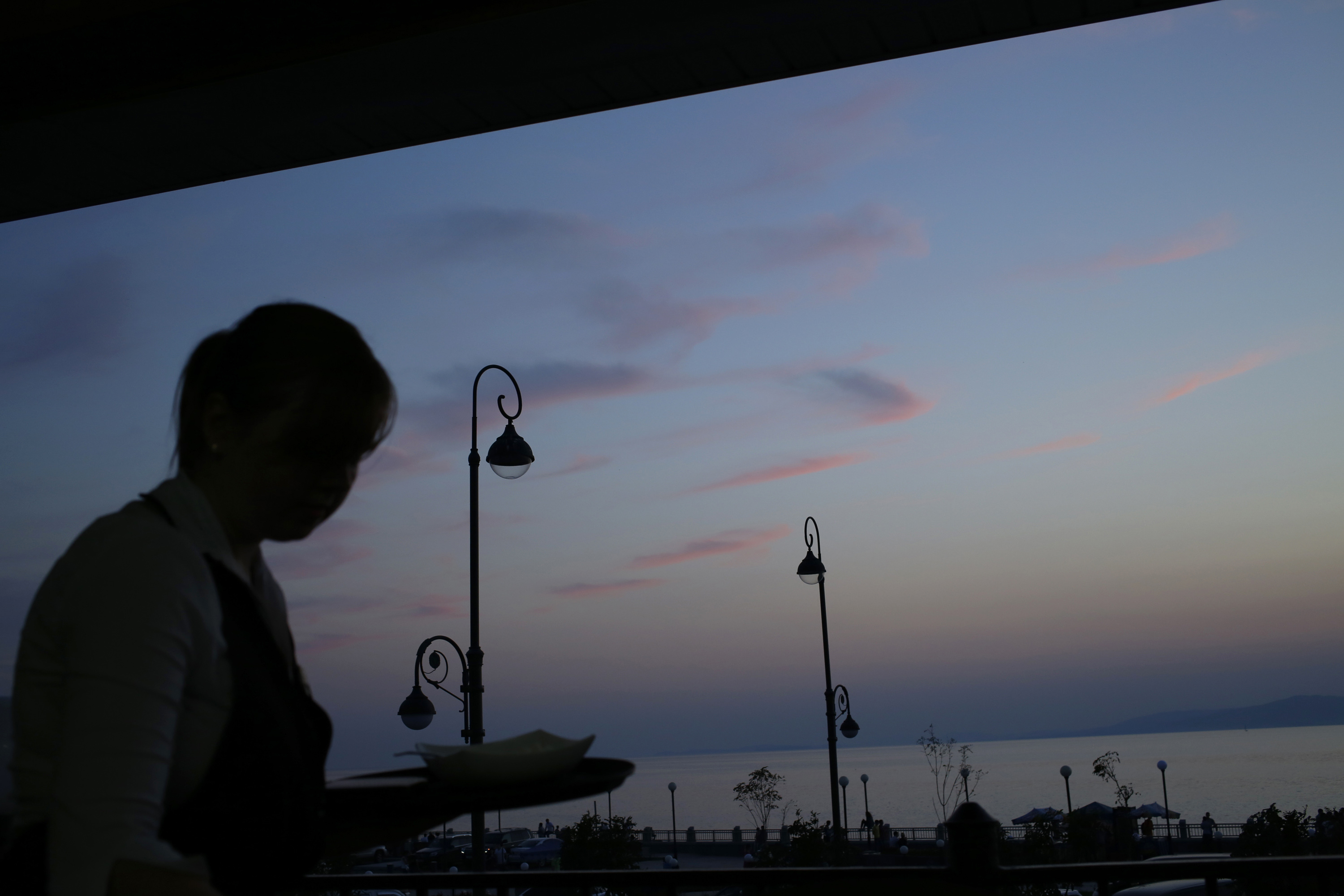 A waitress cleans a table against sunset at a restaurant in the eastern Russian city of Vladivostok, Monday, Sept. 10, 2012. (AP Photo/Vincent Yu)